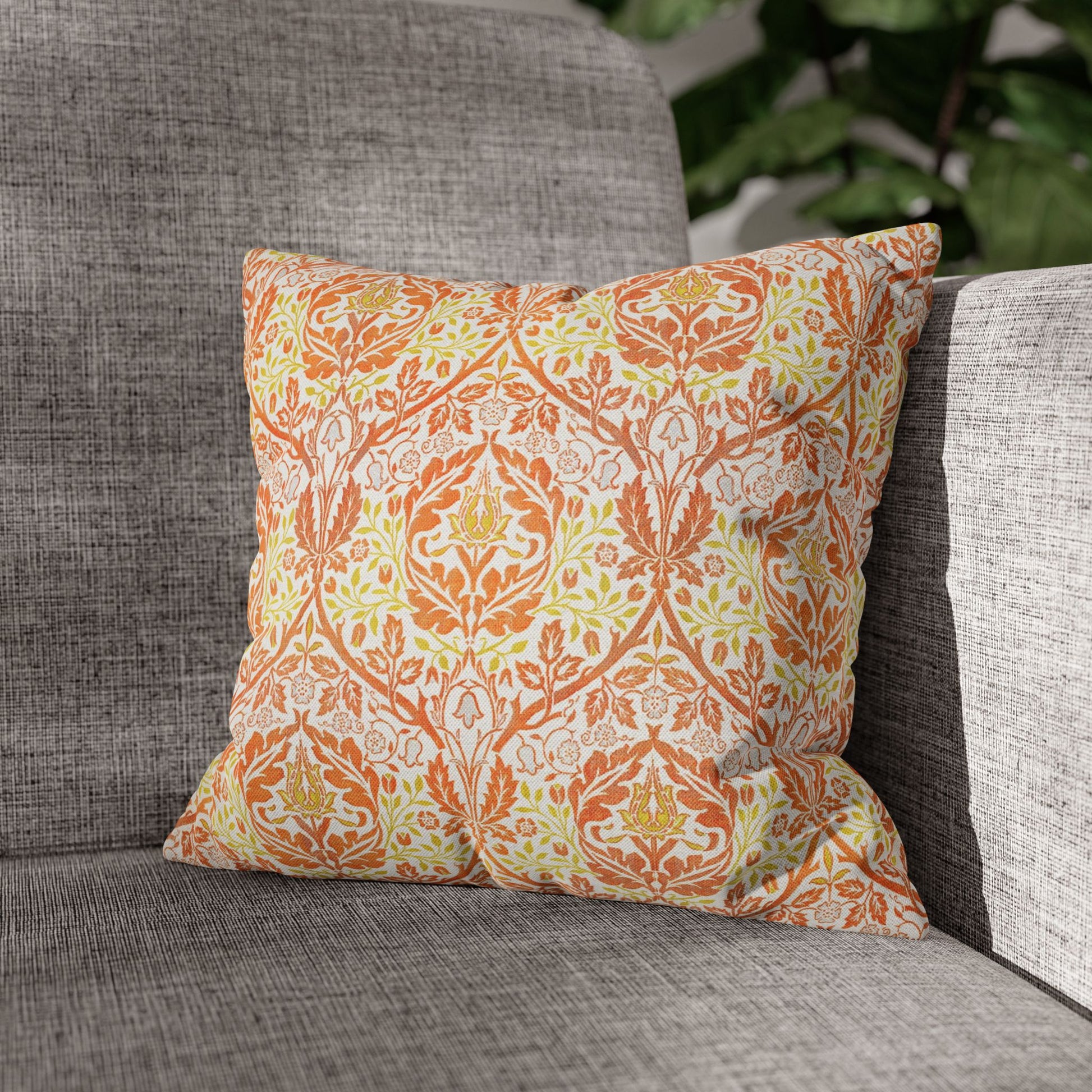 Decorative pillow with orange and green pattern on a gray couch - William Morris Golden Bough