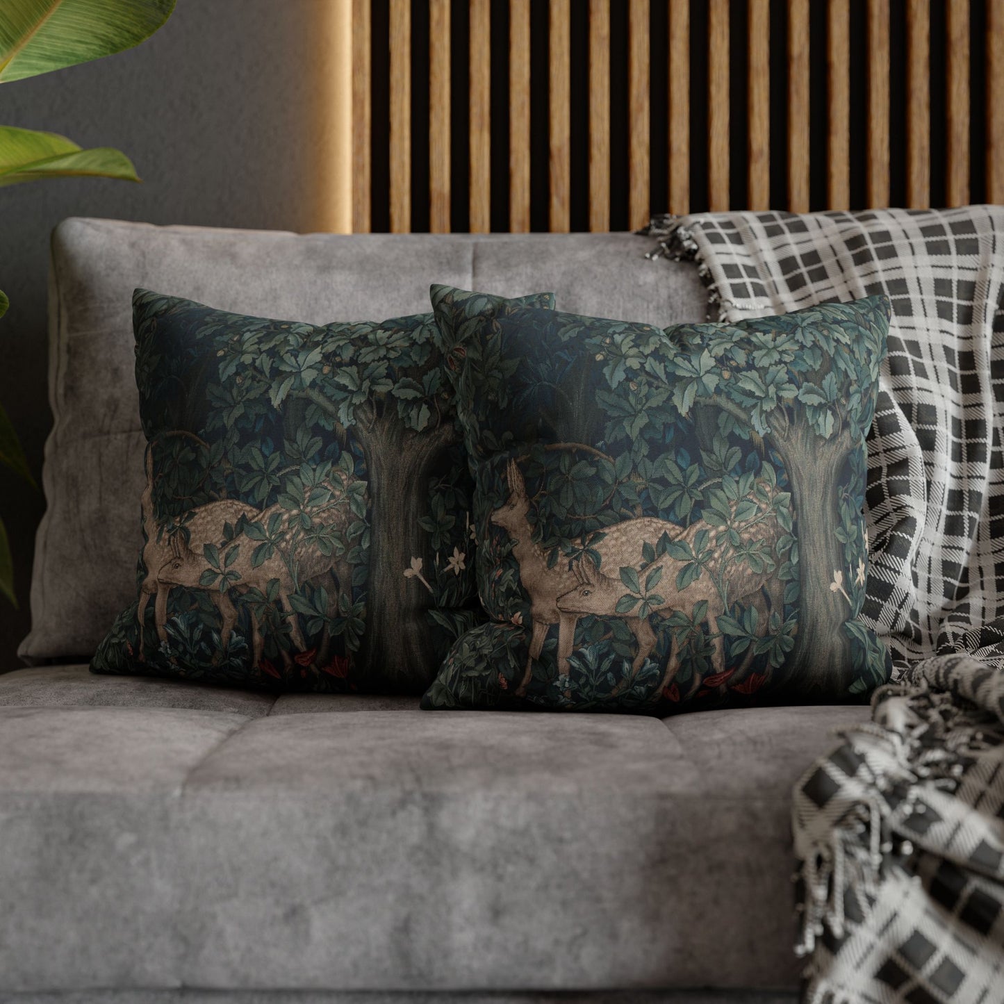 Decorative pillows with deer design on a gray sofa against a wooden panel wall.