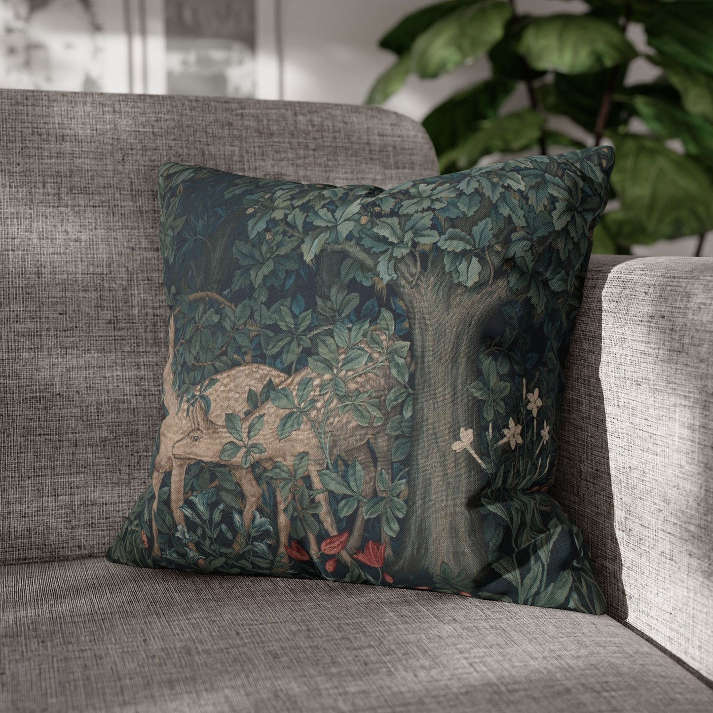 Decorative pillow with a nature-themed design featuring a deer and trees on a gray sofa.
