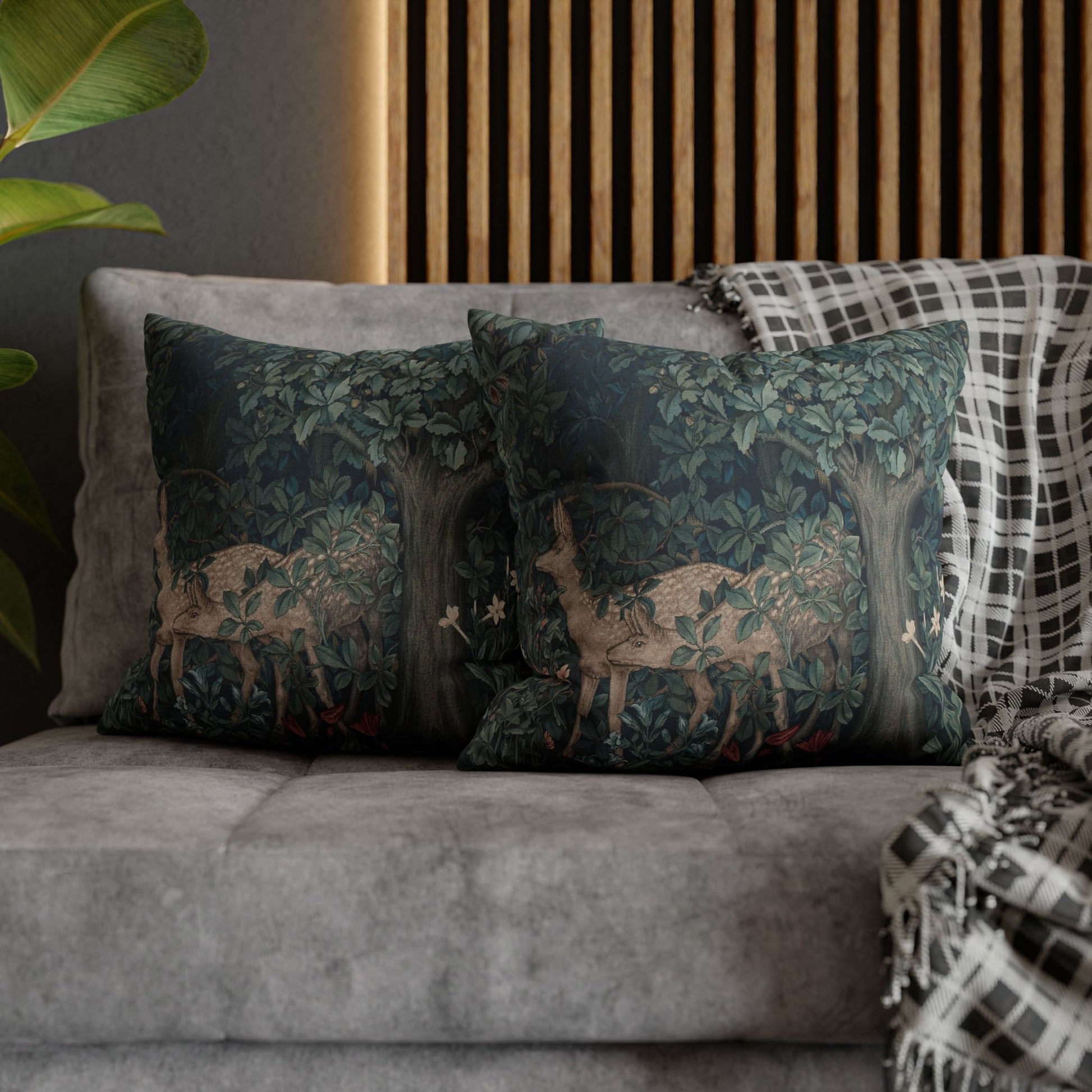 Decorative pillows with deer design on a gray sofa against a wooden panel wall.