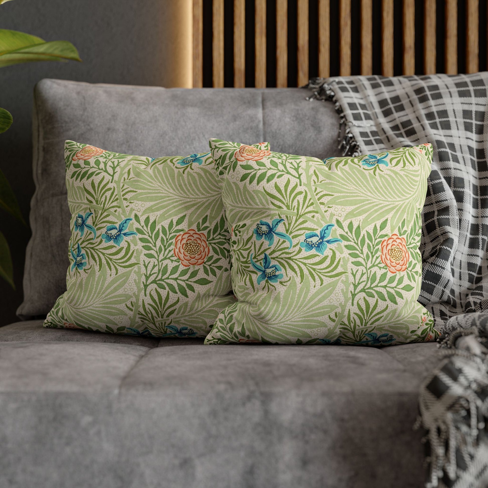 Floral patterned pillows on a gray sofa with a wooden headboard in the background.