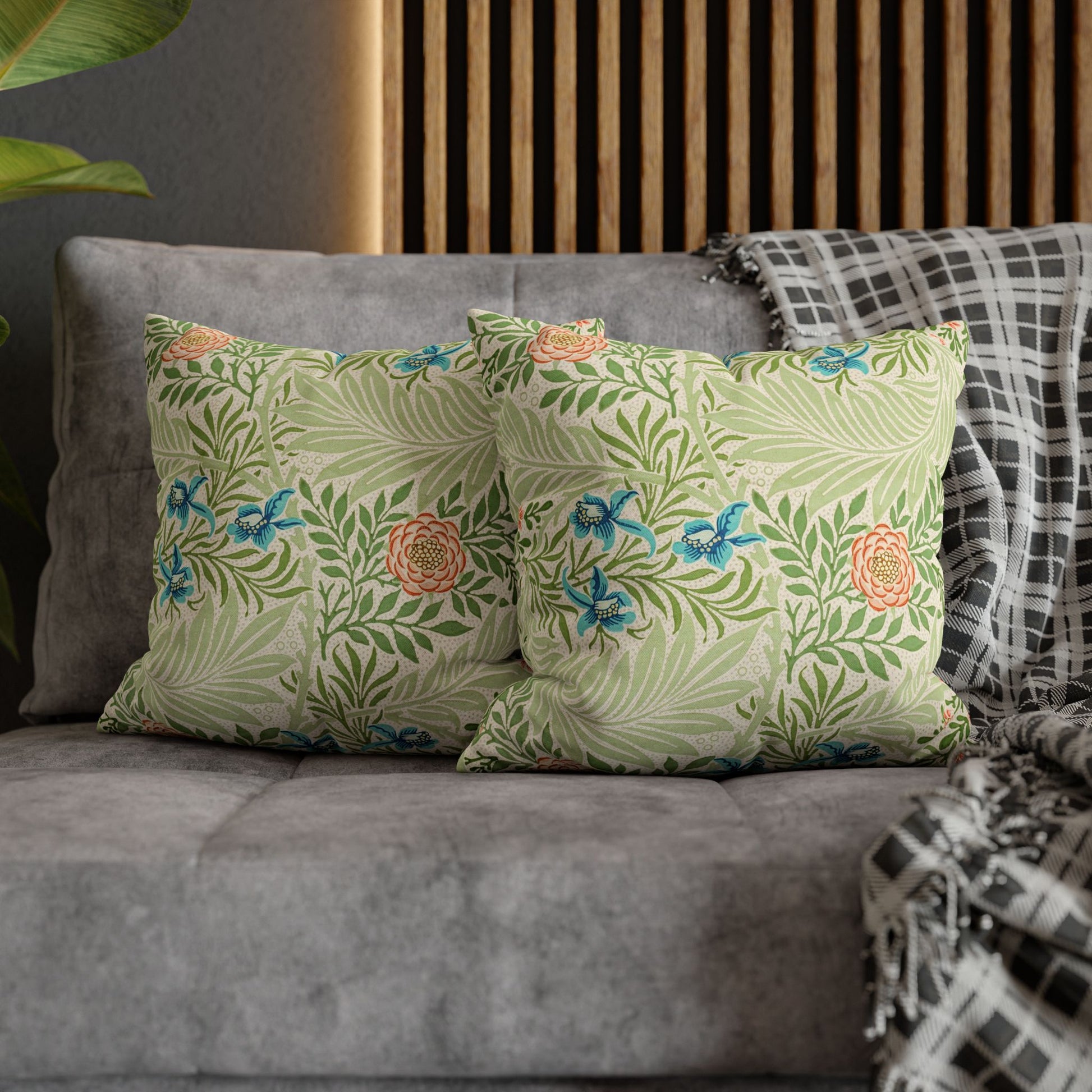 Floral-patterned pillows on a gray sofa with a wooden headboard in the background.