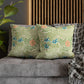 Floral patterned pillows on a gray sofa with a wooden headboard and plant in the background