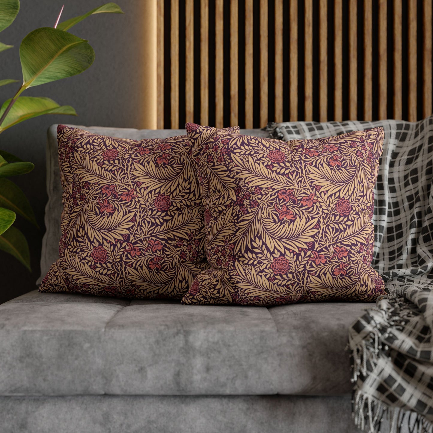 Decorative pillows with floral pattern on a gray sofa against a wooden headboard.