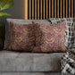 Floral patterned pillows on a gray sofa with a wooden headboard in the background.