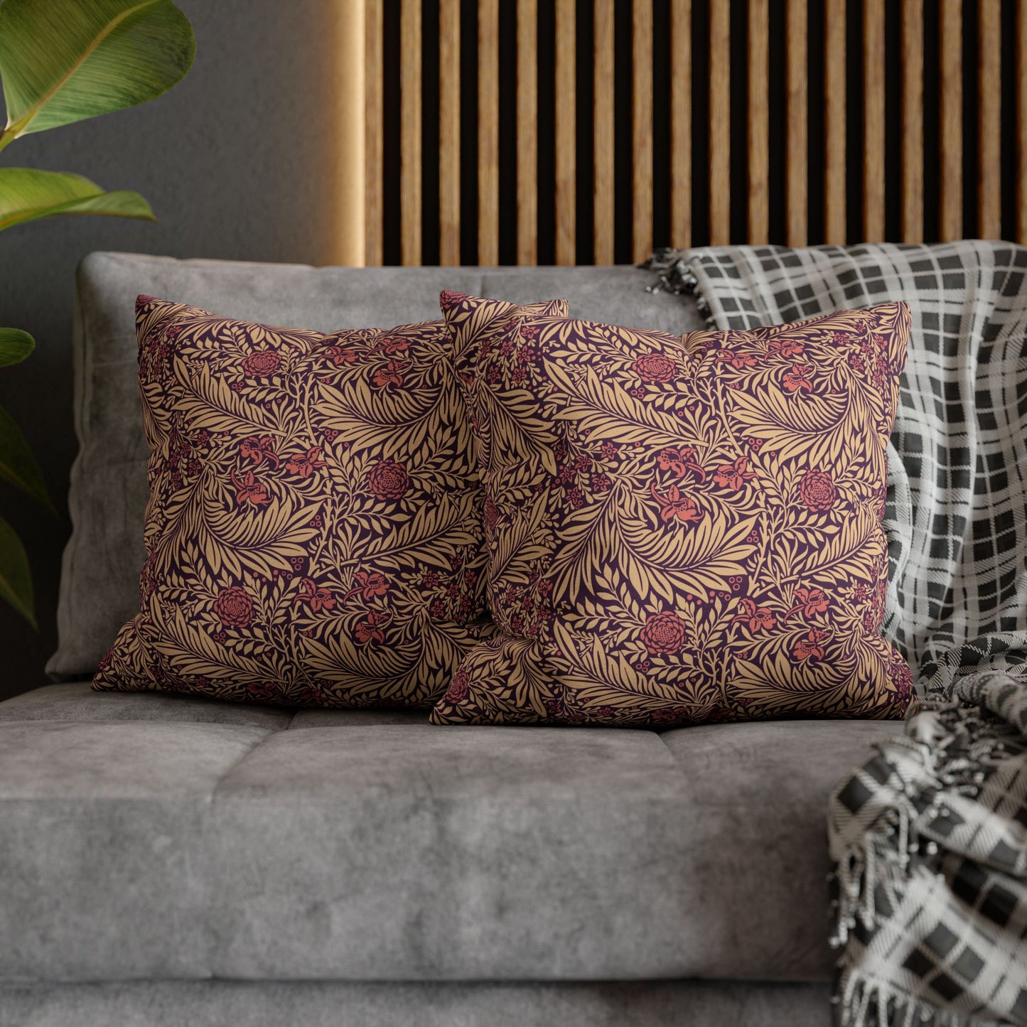 Floral patterned pillows on a gray sofa with a wooden headboard in the background.