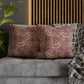 Decorative pillows with floral pattern on a gray sofa against a wooden headboard.