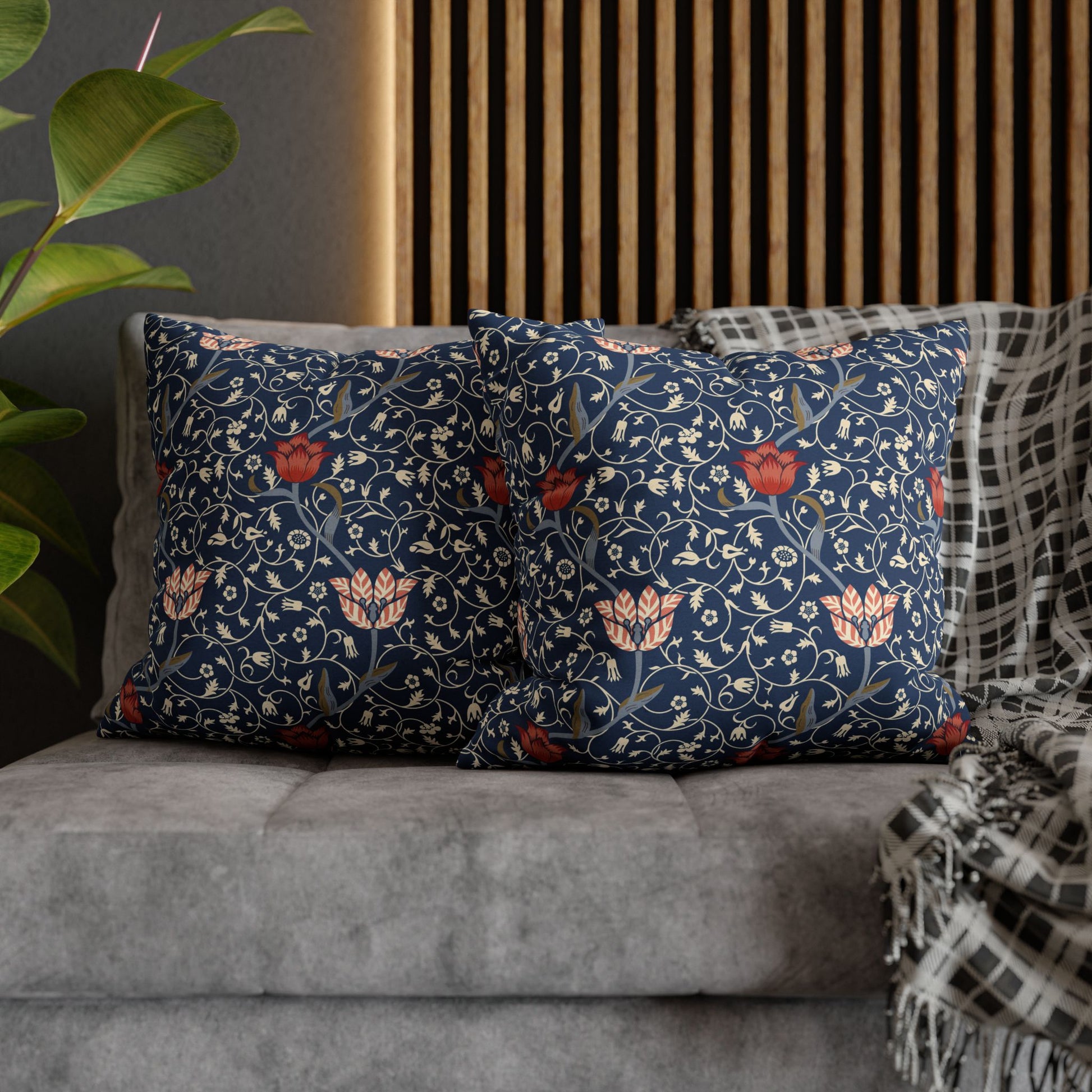 Floral patterned cushions on a sofa with a plant and wooden headboard in the background