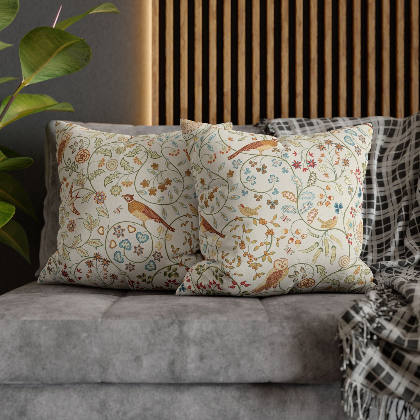 Decorative pillows with floral and bird pattern on a gray sofa.