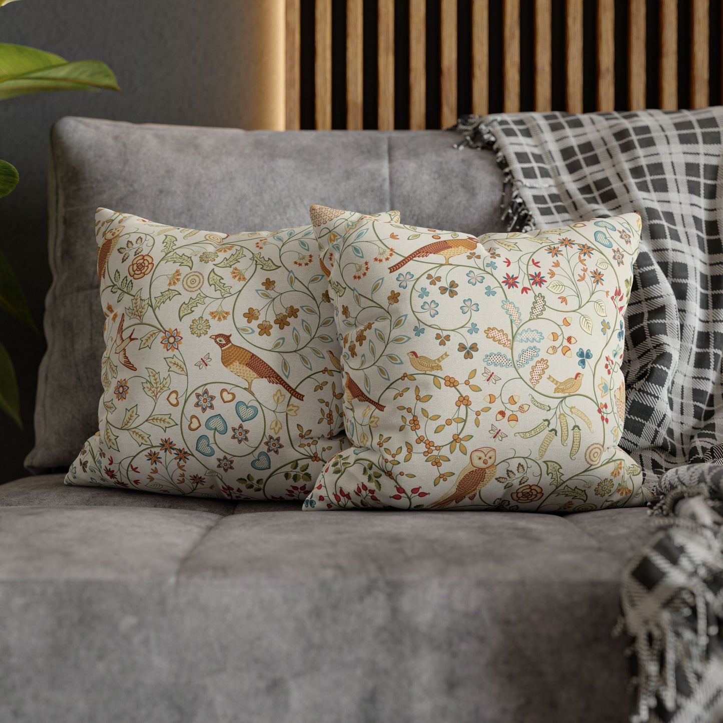 Decorative pillows with floral and bird pattern on a gray sofa.