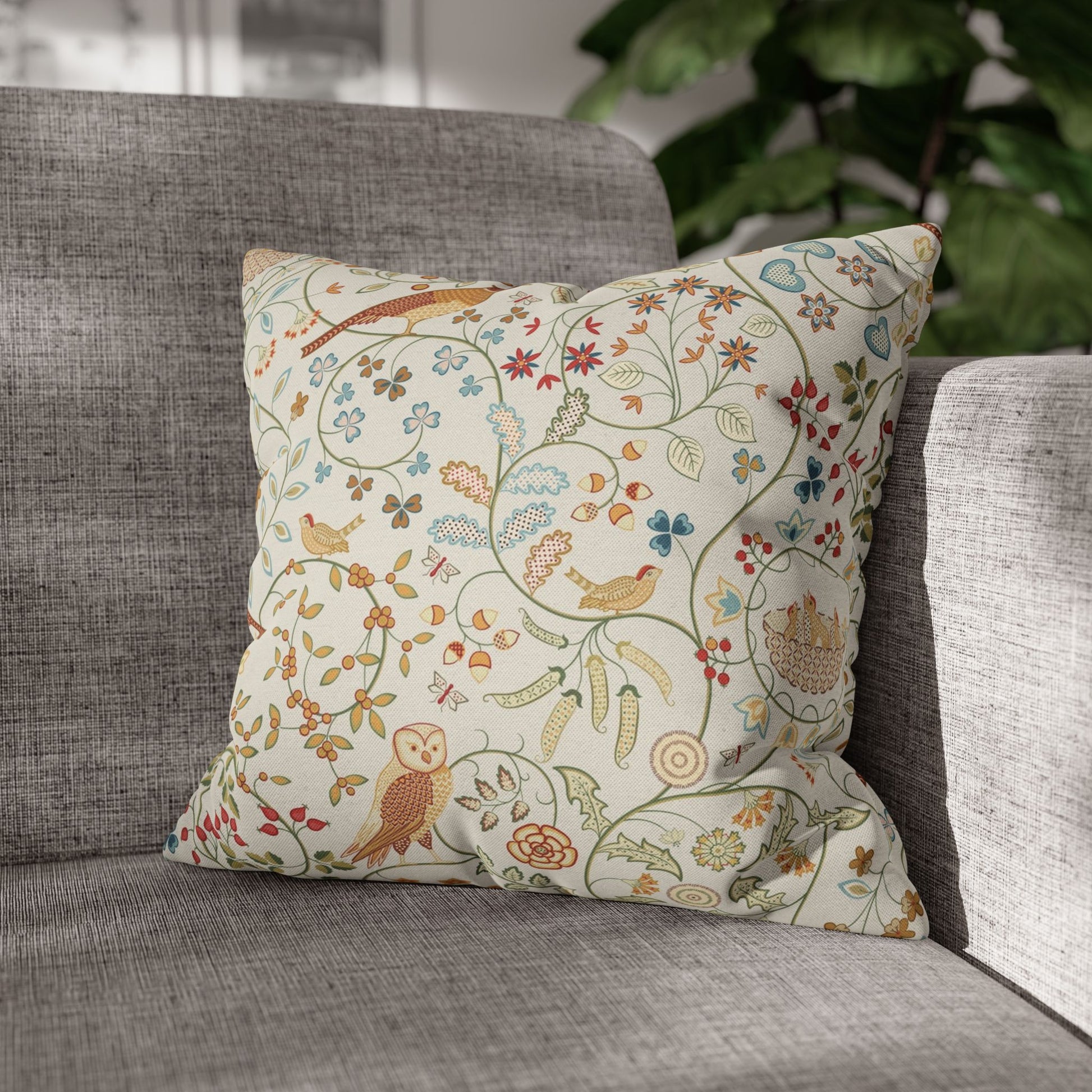 Decorative pillow with floral and bird pattern on a gray sofa
