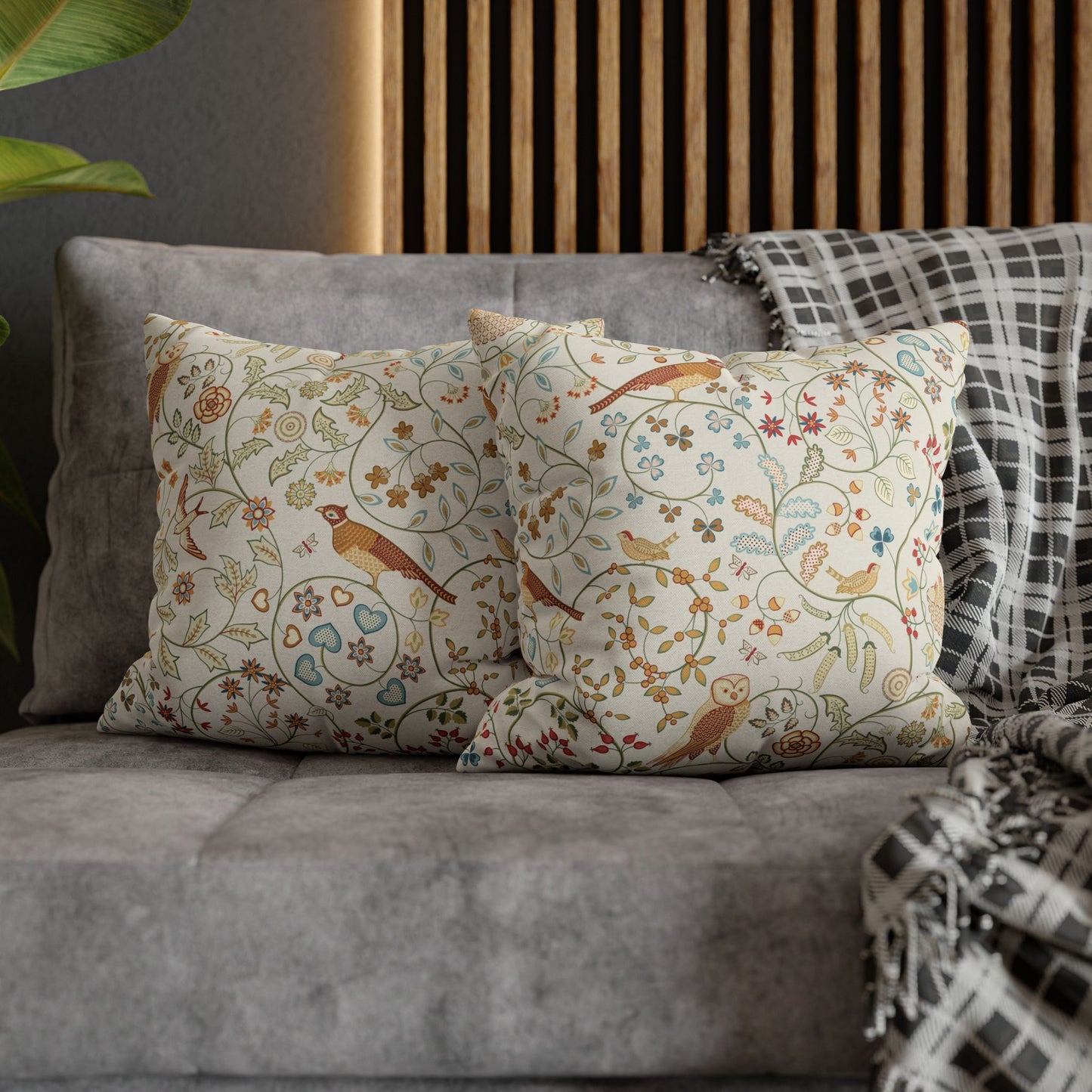 Decorative pillows with floral and bird pattern on a gray sofa.