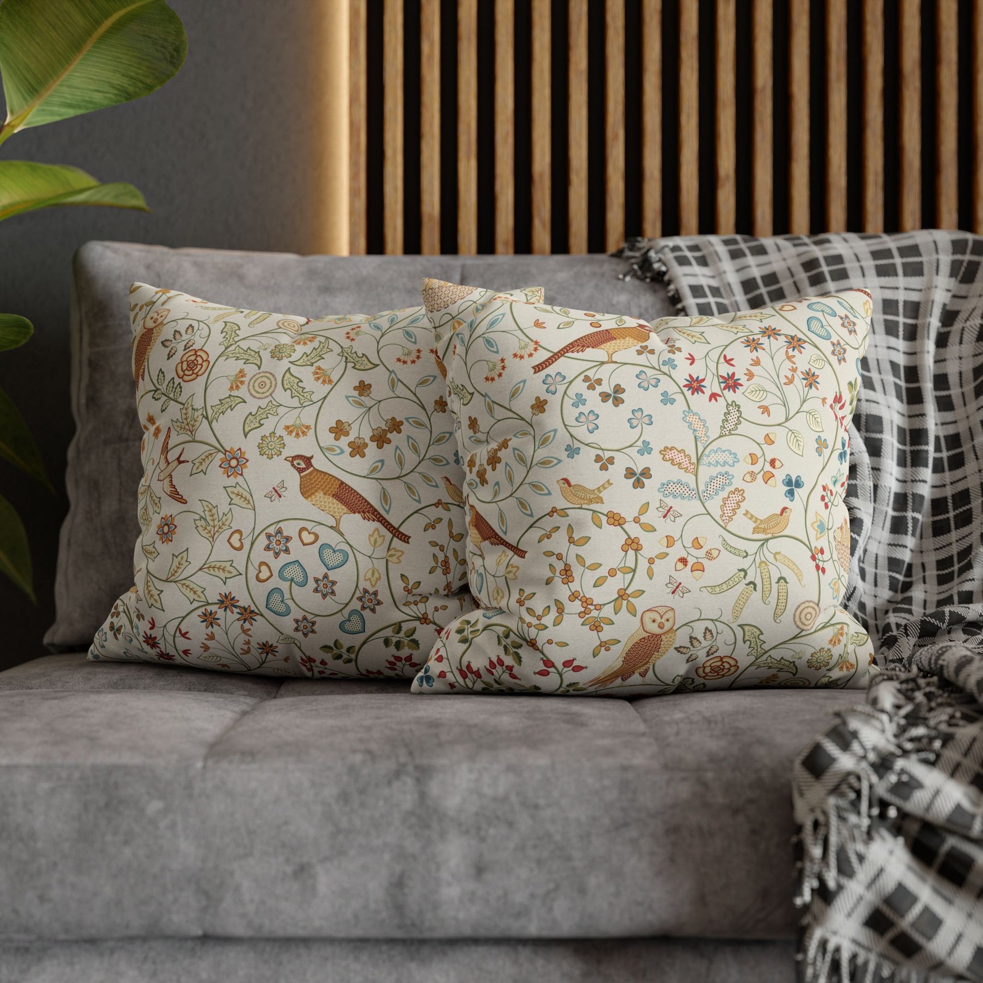 Decorative pillows with floral and bird pattern on a gray sofa.