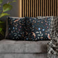 Decorative pillows with floral and bird patterns on a gray sofa.