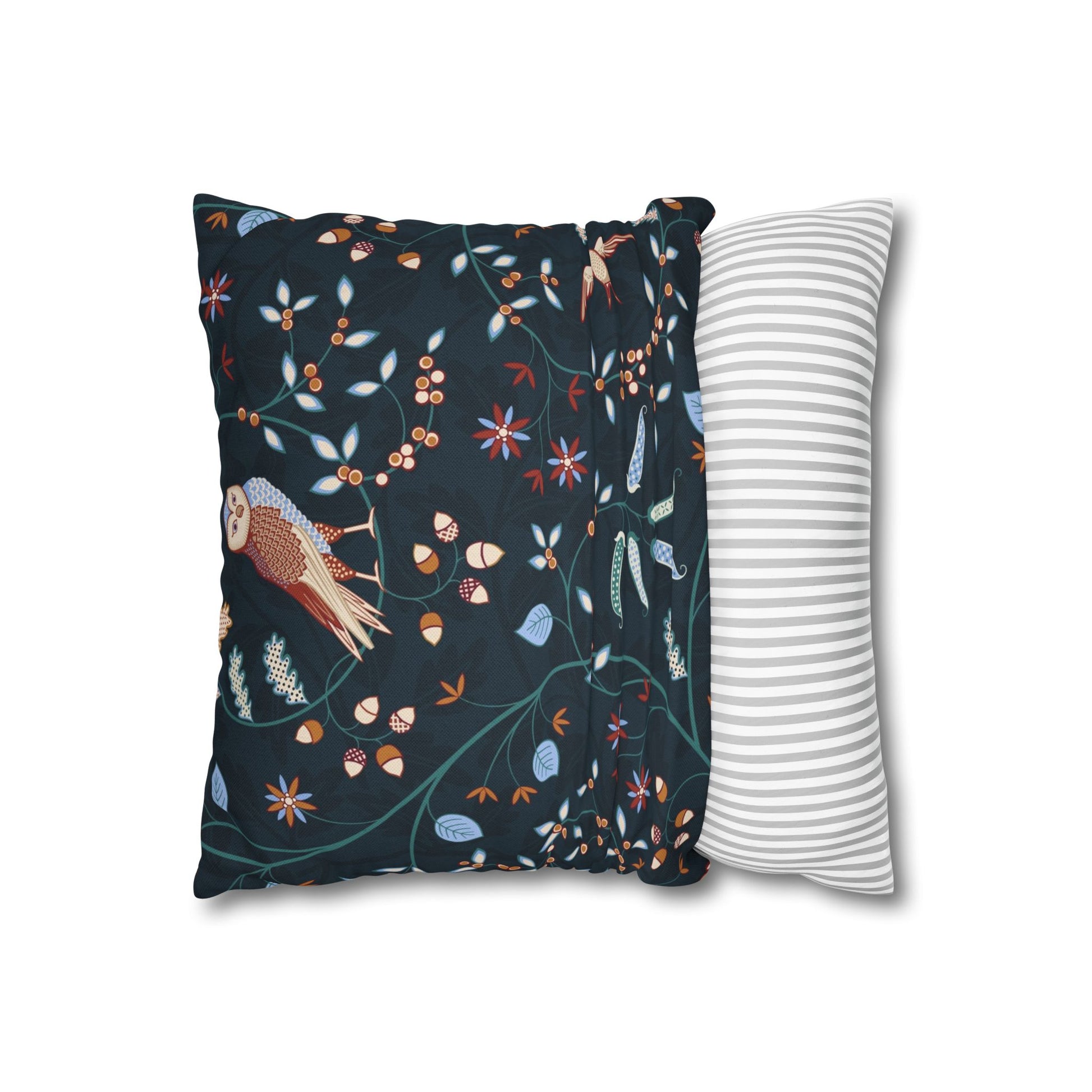 Decorative pillow with nature-themed design next to a plain striped pillow on a white background