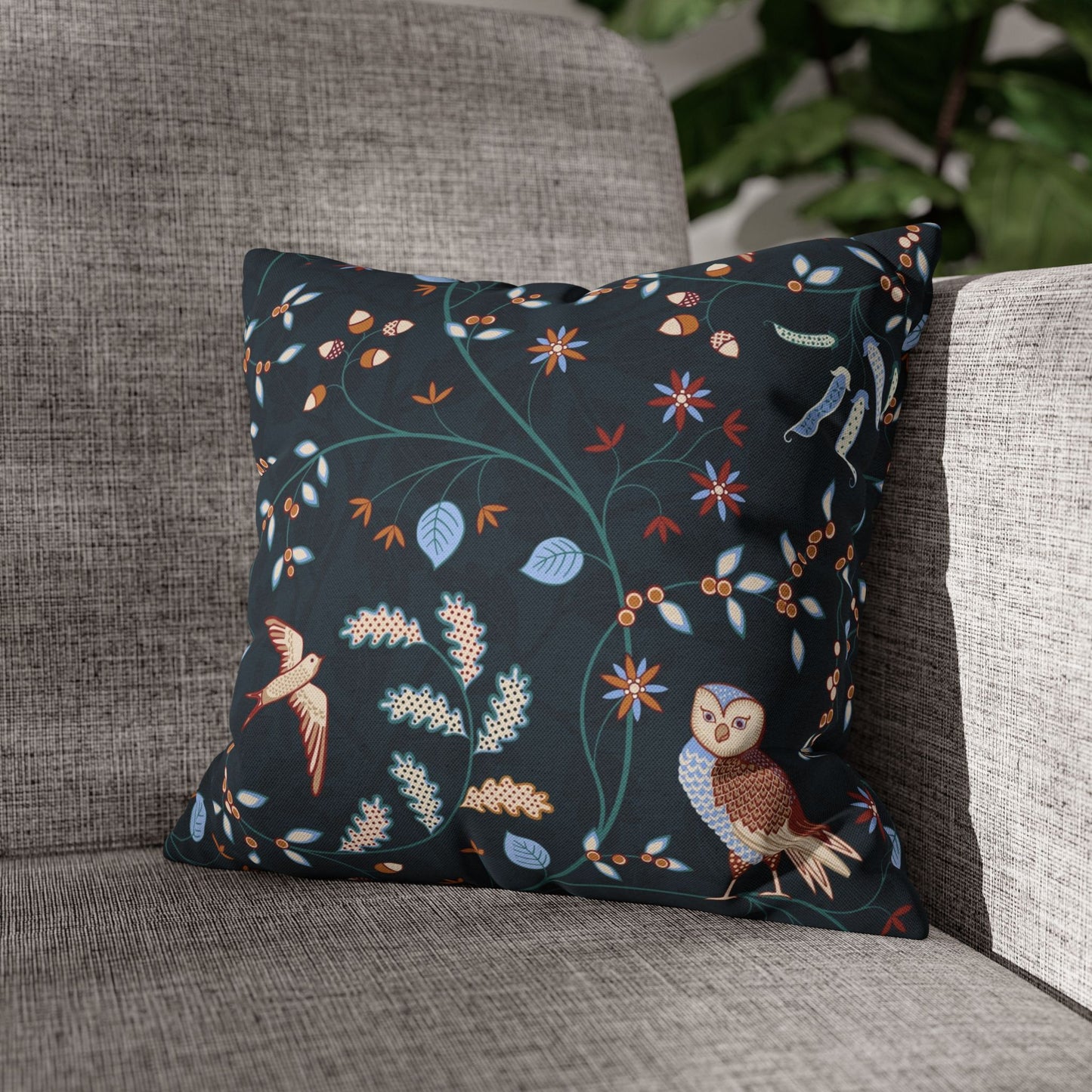 Decorative pillow with owl and floral pattern on a gray sofa