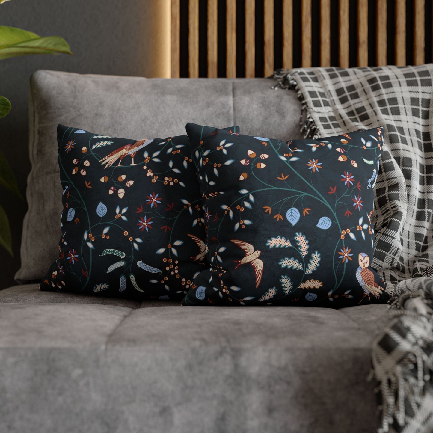 Decorative pillows with floral and bird pattern on a gray sofa.