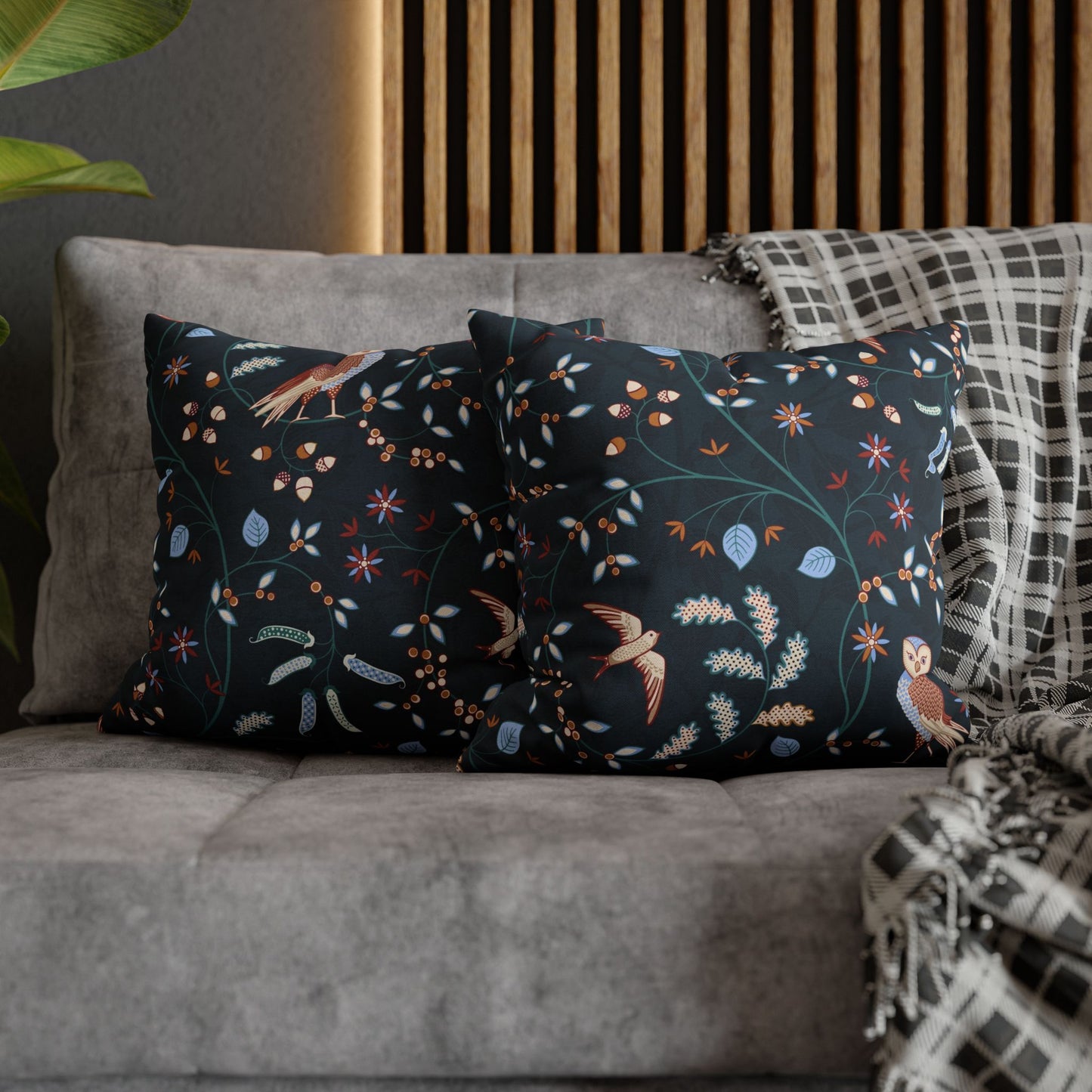 Decorative pillows with floral and bird patterns on a gray sofa.