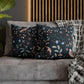 Decorative pillows with floral patterns on a gray sofa against a wooden panel wall.