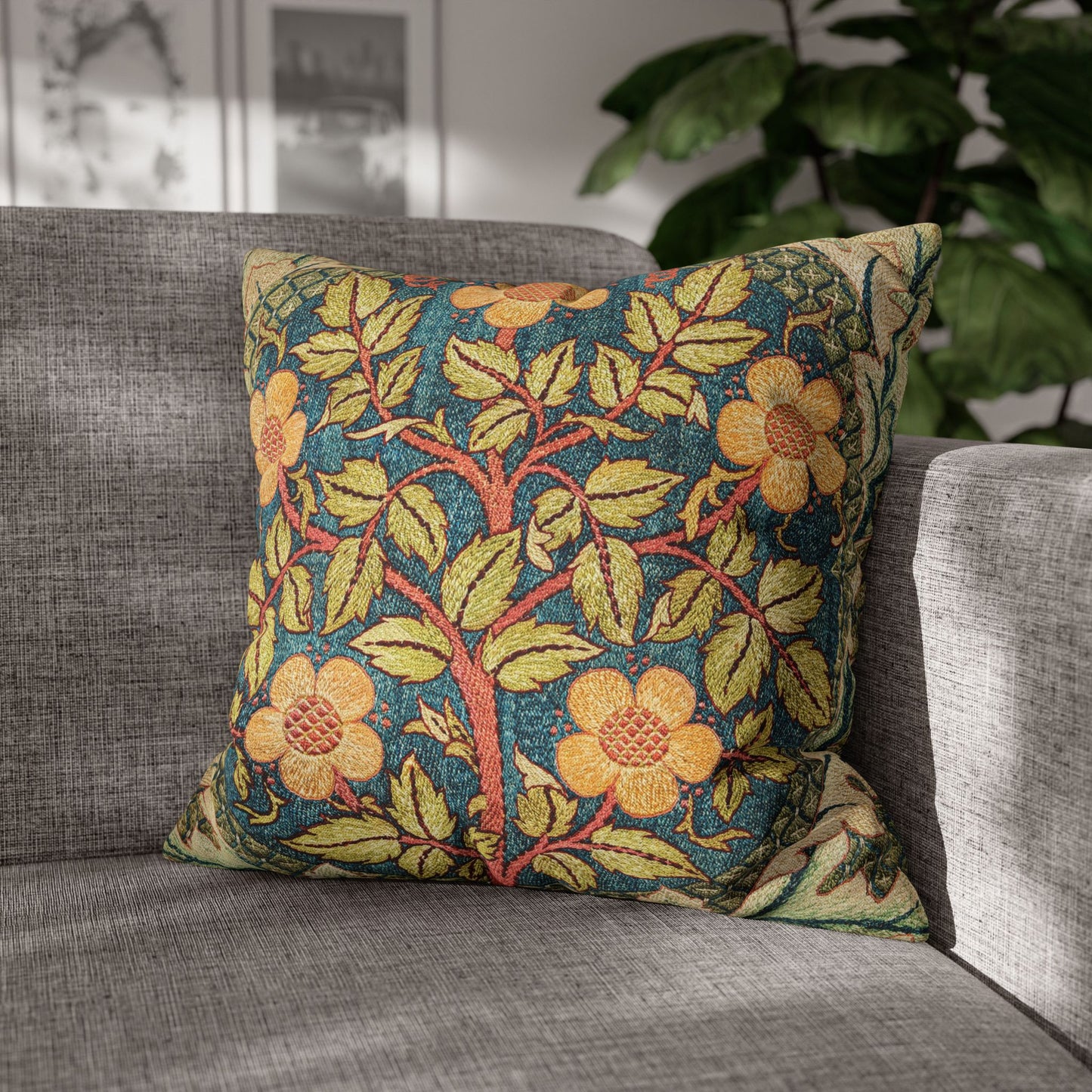 Decorative floral pillow on a gray sofa with a plant in the background