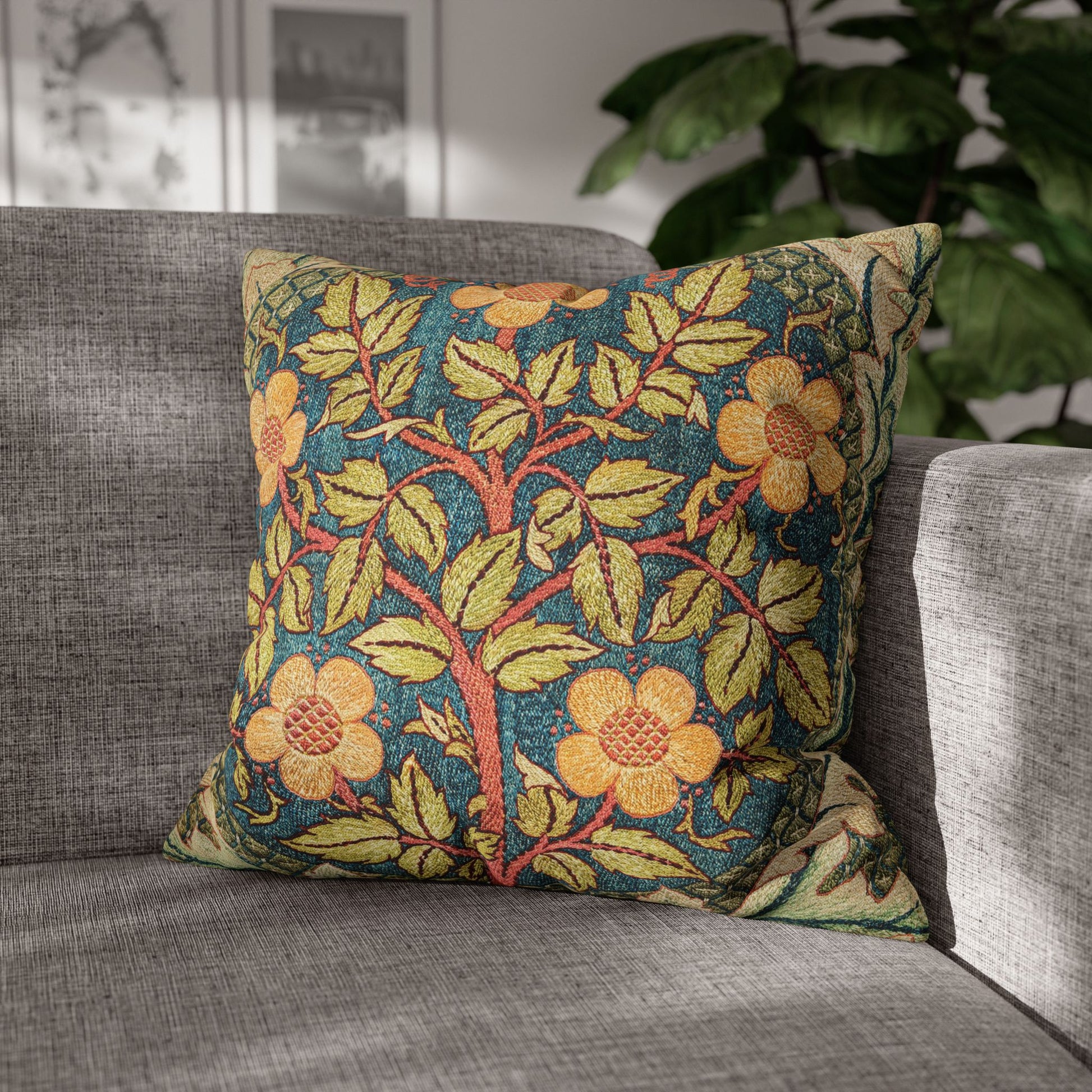Decorative floral pillow on a gray sofa with a plant in the background