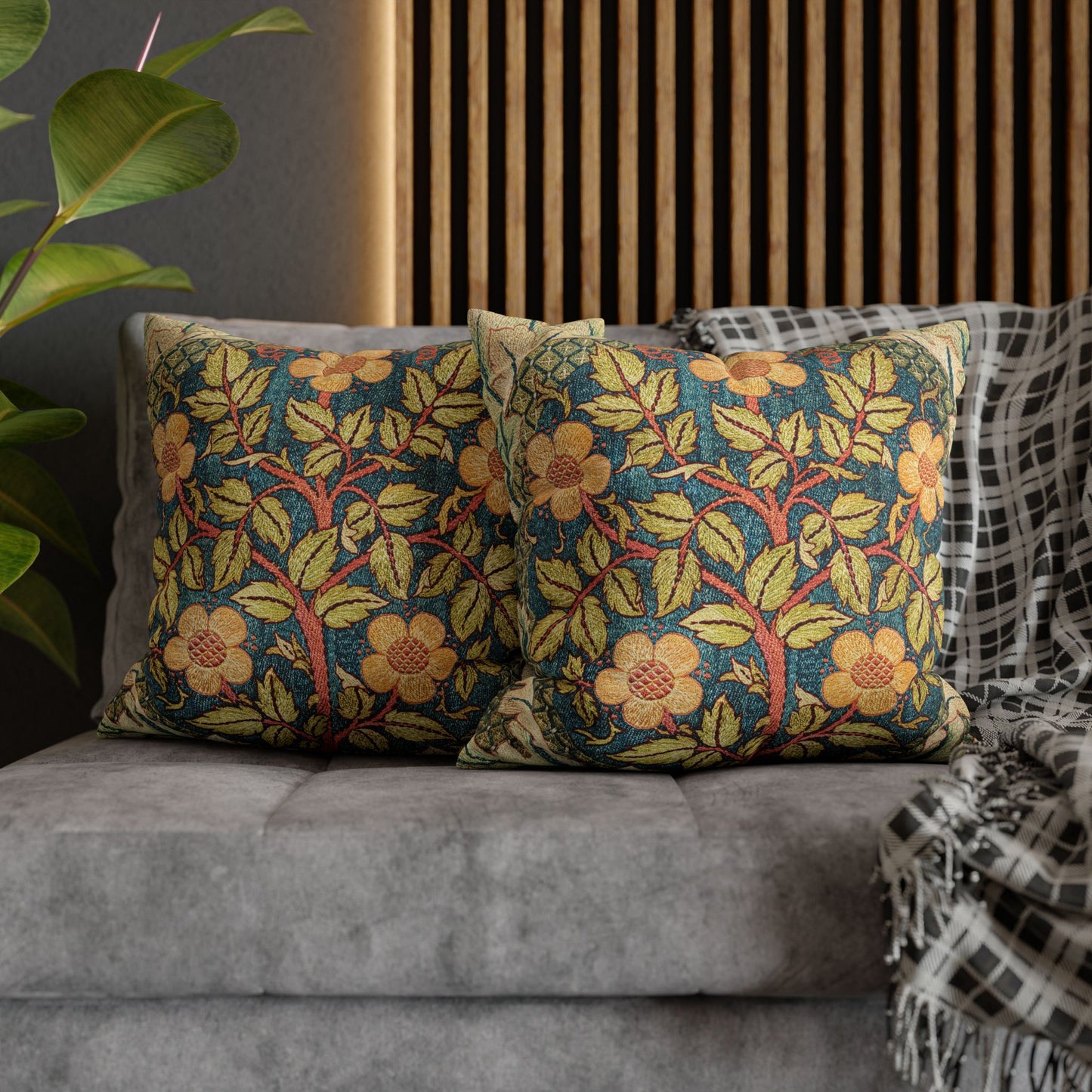 Floral patterned cushions on a gray sofa with a plant and wooden panel in the background