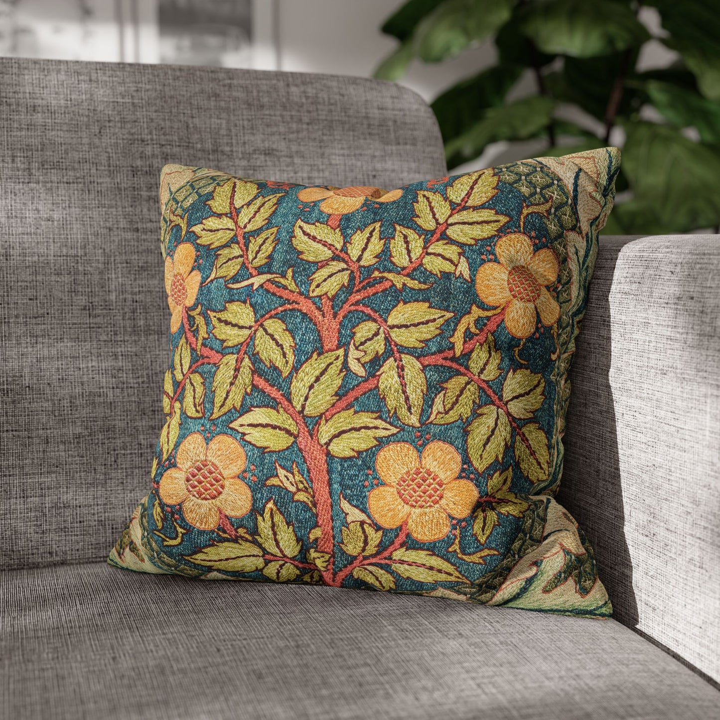 Decorative floral pillow on a gray sofa with a blurred plant in the background