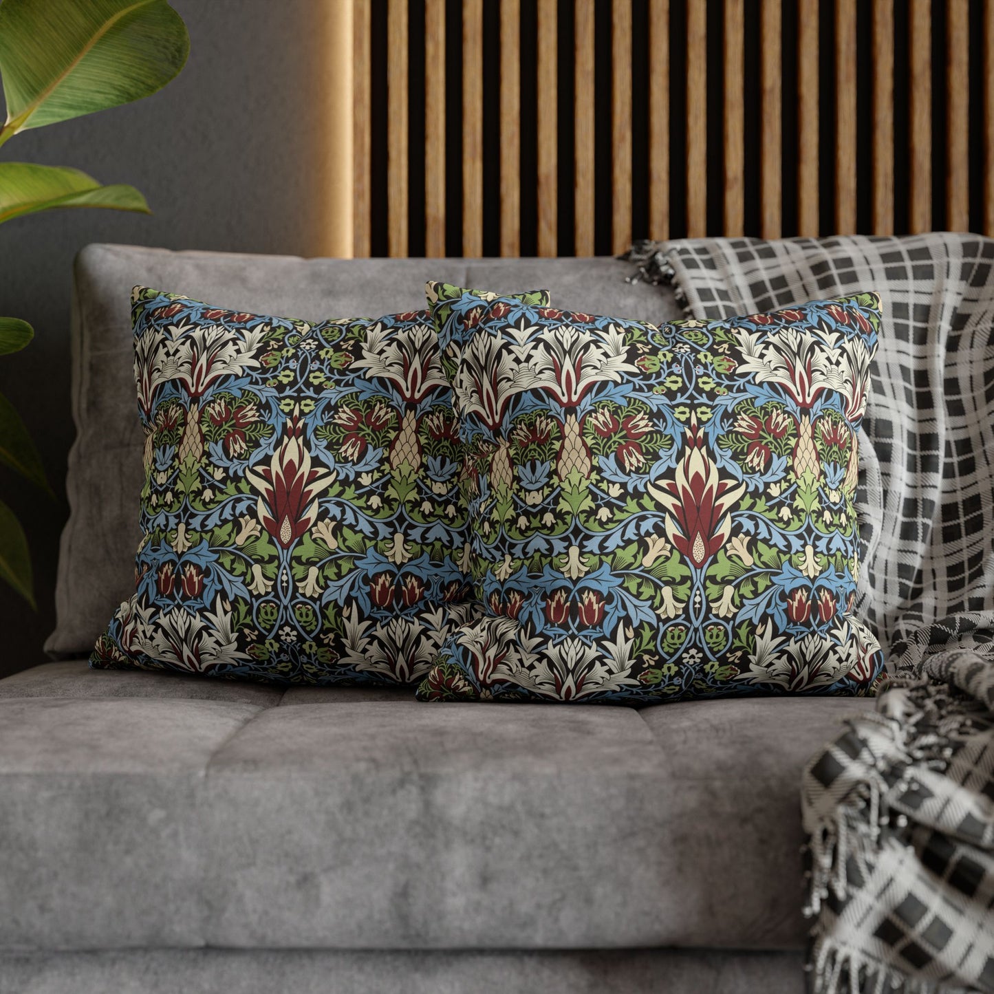 Decorative pillows with a floral pattern on a gray sofa against a wooden panel wall - William Morris Snakeshead