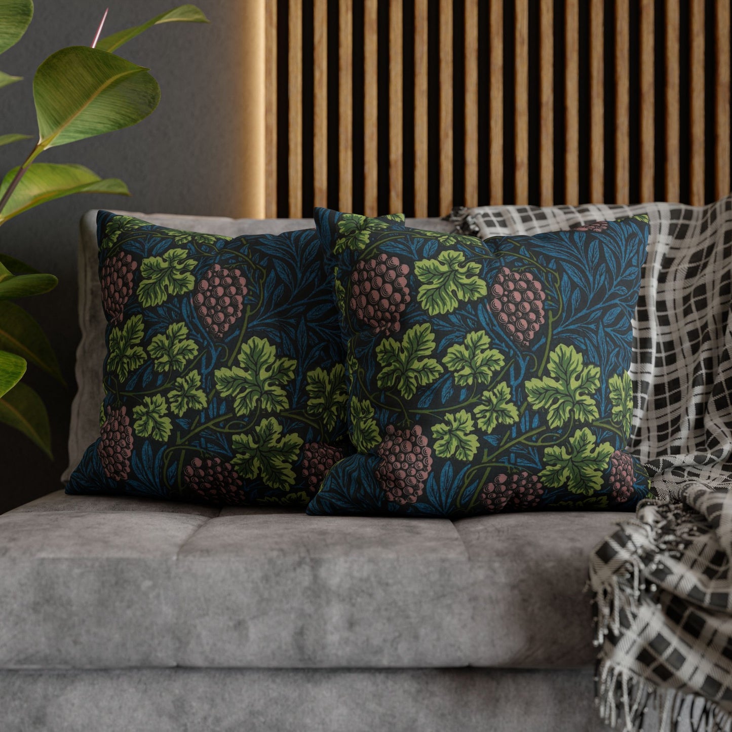 Decorative pillows with floral pattern on a gray sofa against a wooden slat wall.