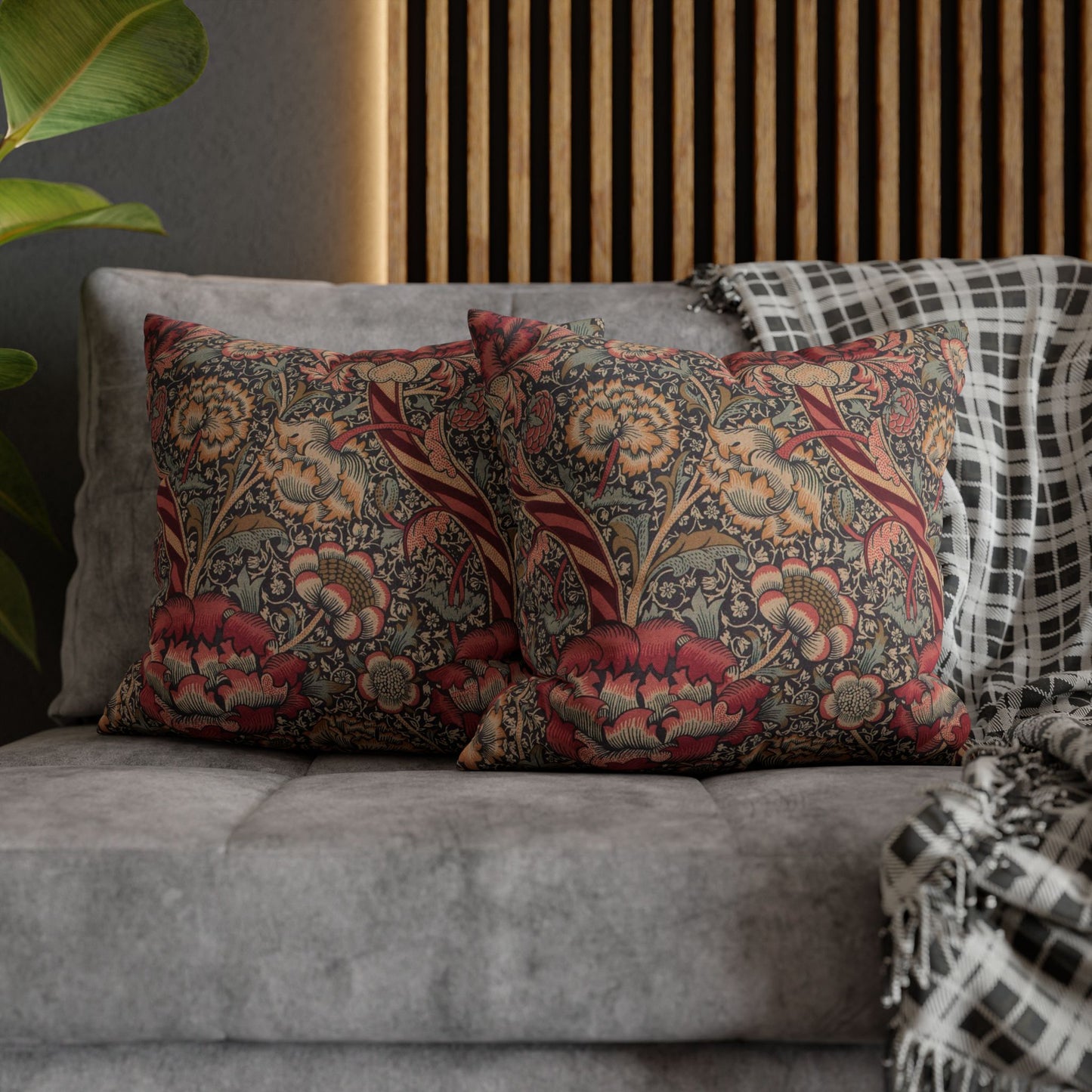 Decorative pillows with floral patterns on a gray sofa against a wooden panel background.