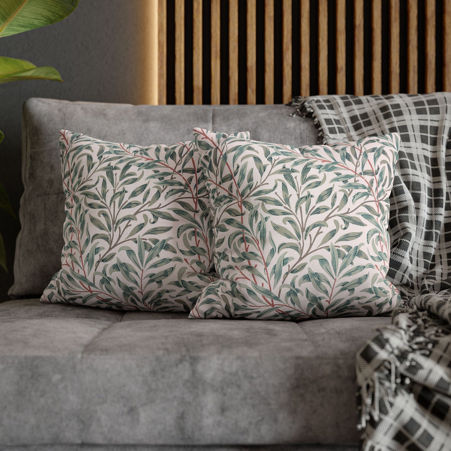 Decorative pillows with leaf patterns on a gray sofa against a wooden headboard.