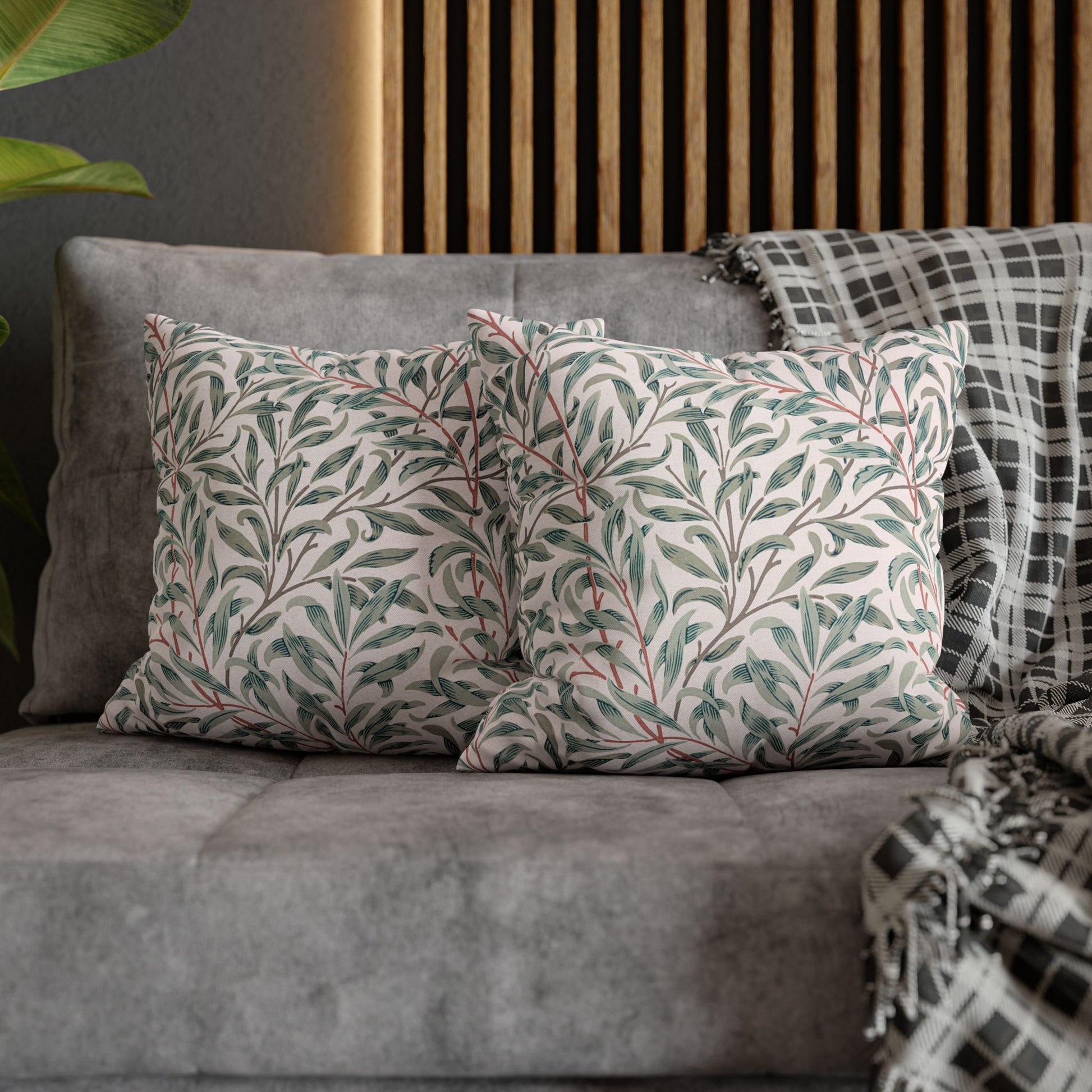 Decorative pillows with leaf patterns on a gray sofa against a wooden headboard.