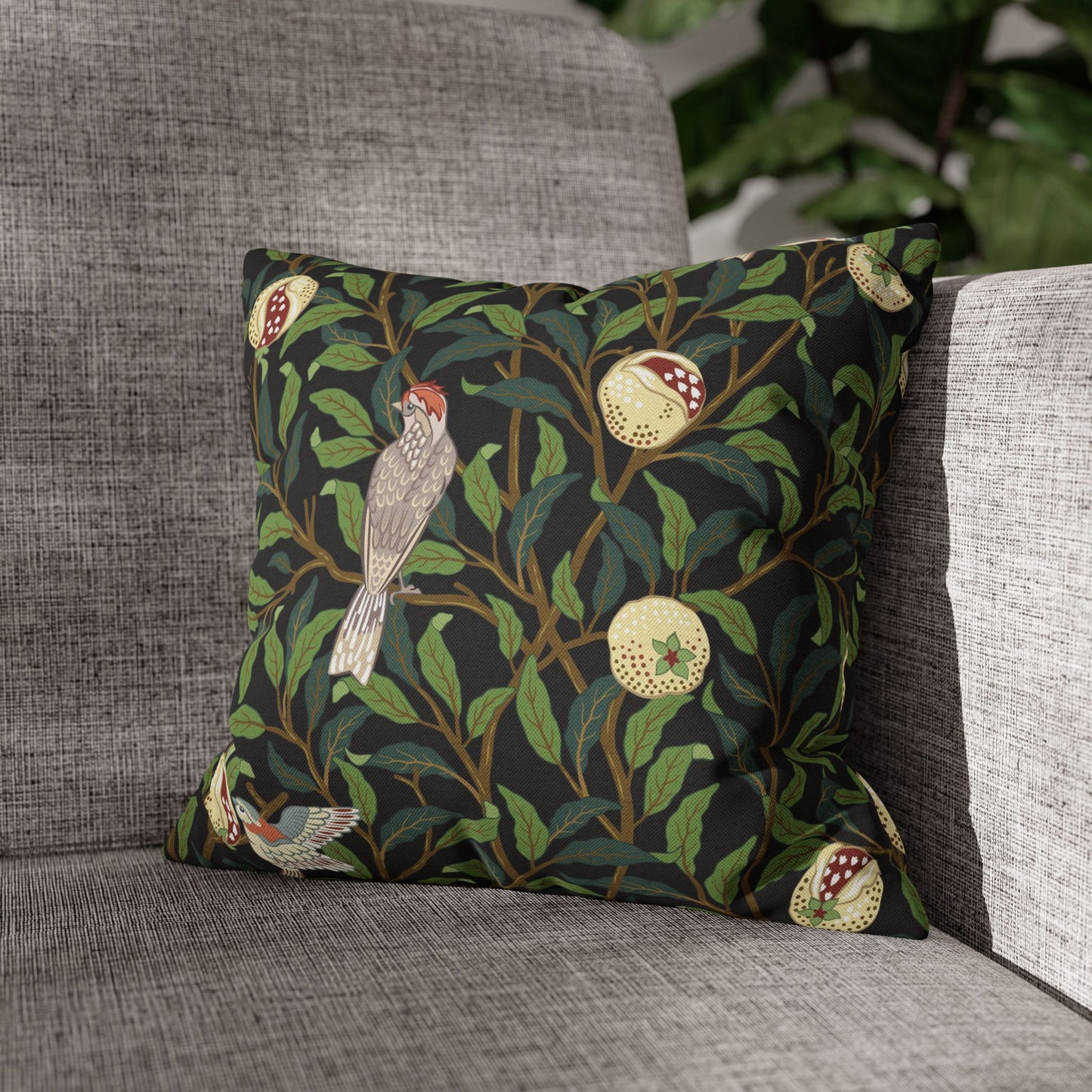 Decorative pillow with bird and fruit pattern on a gray sofa
