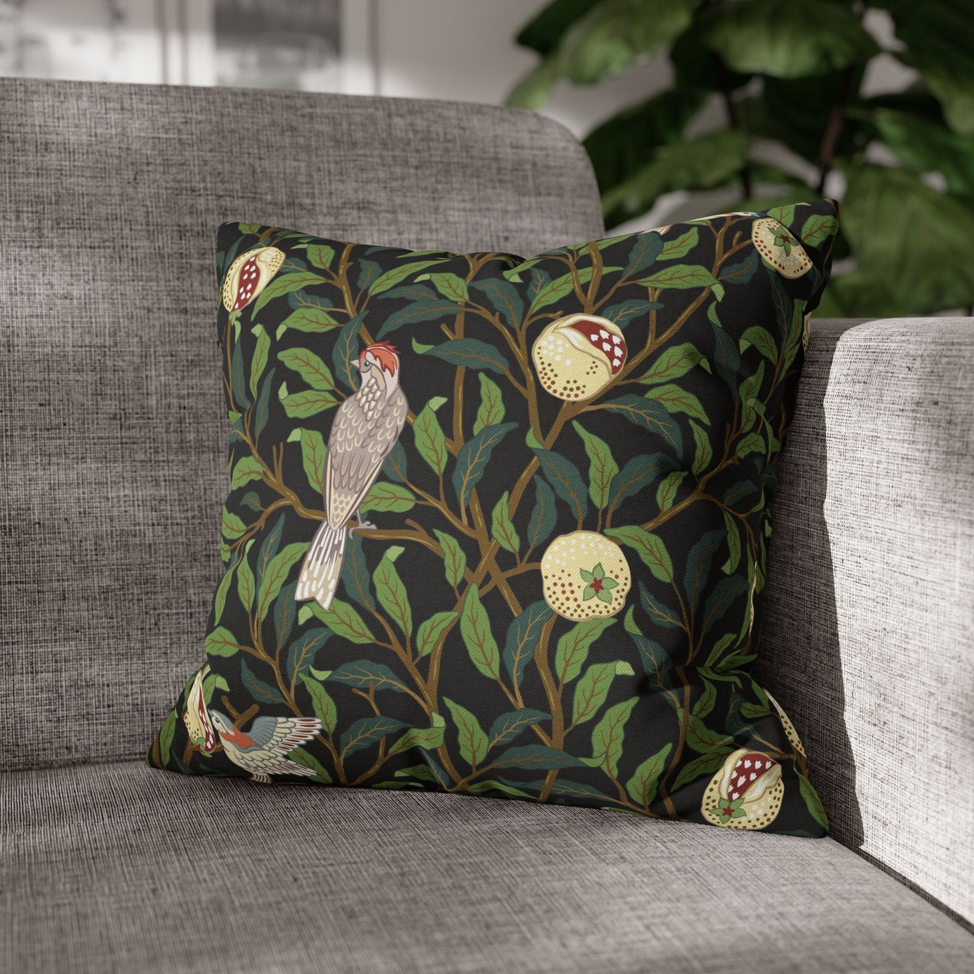 Decorative pillow with bird and apple design on a gray sofa