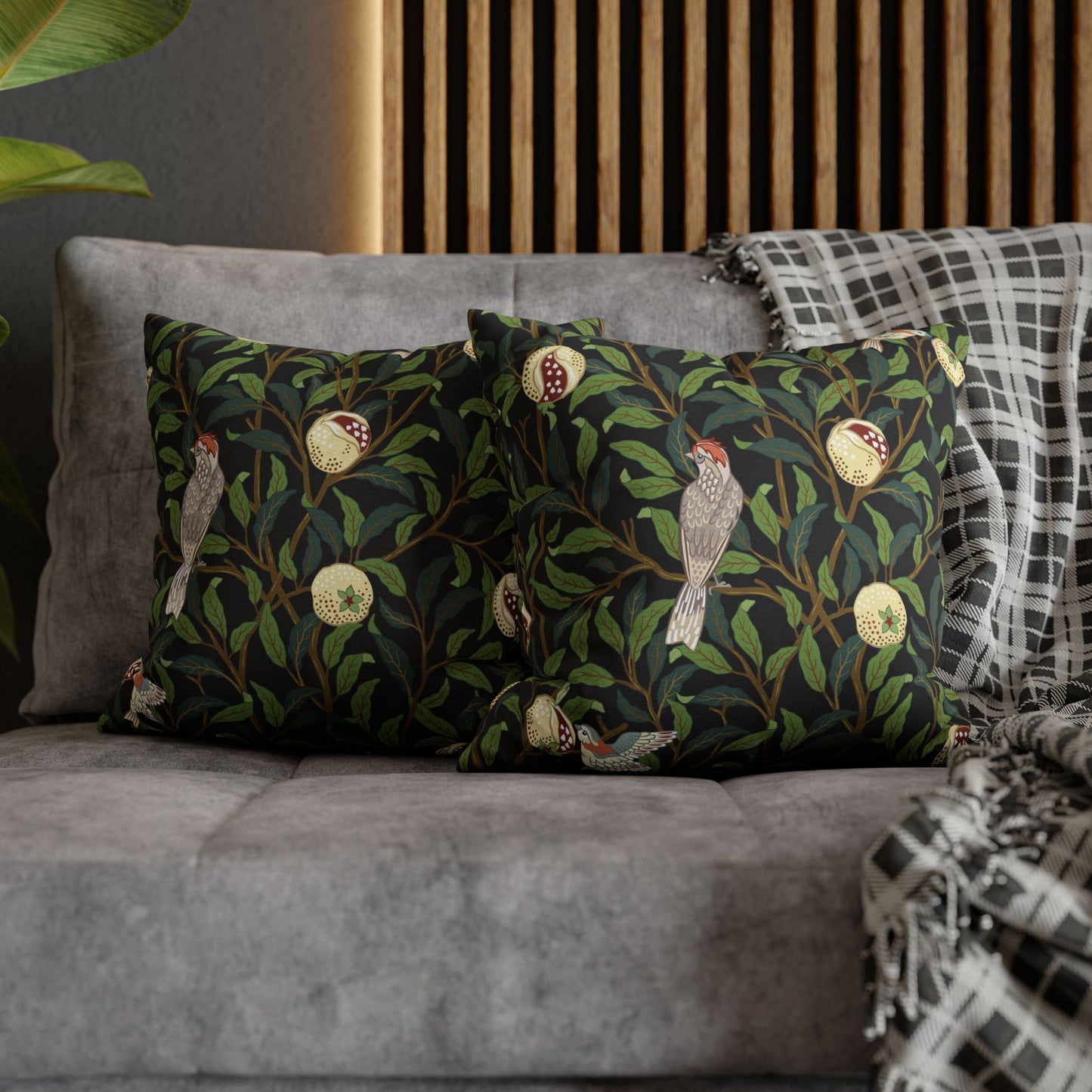 Decorative pillows with bird and leaf pattern on a gray sofa.