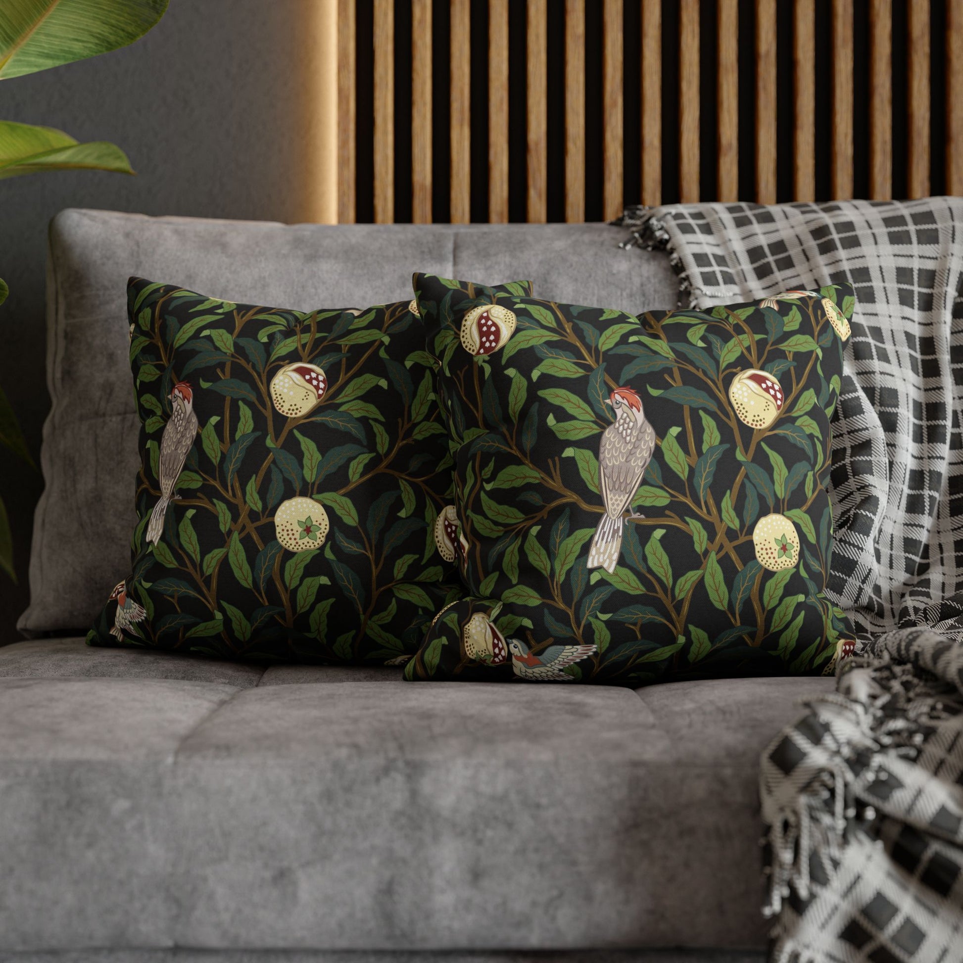 Decorative pillows with bird and leaf pattern on a gray sofa.