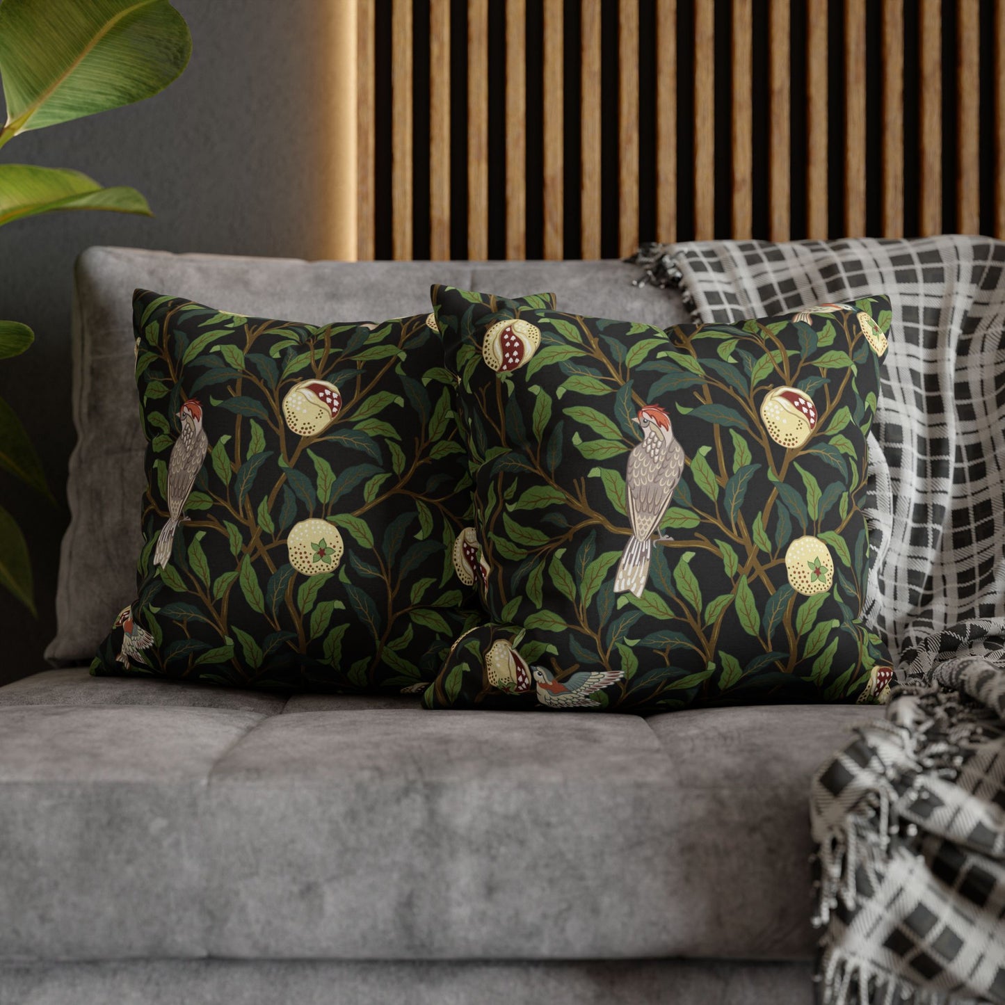 Decorative pillows with bird and leaf pattern on a gray sofa.
