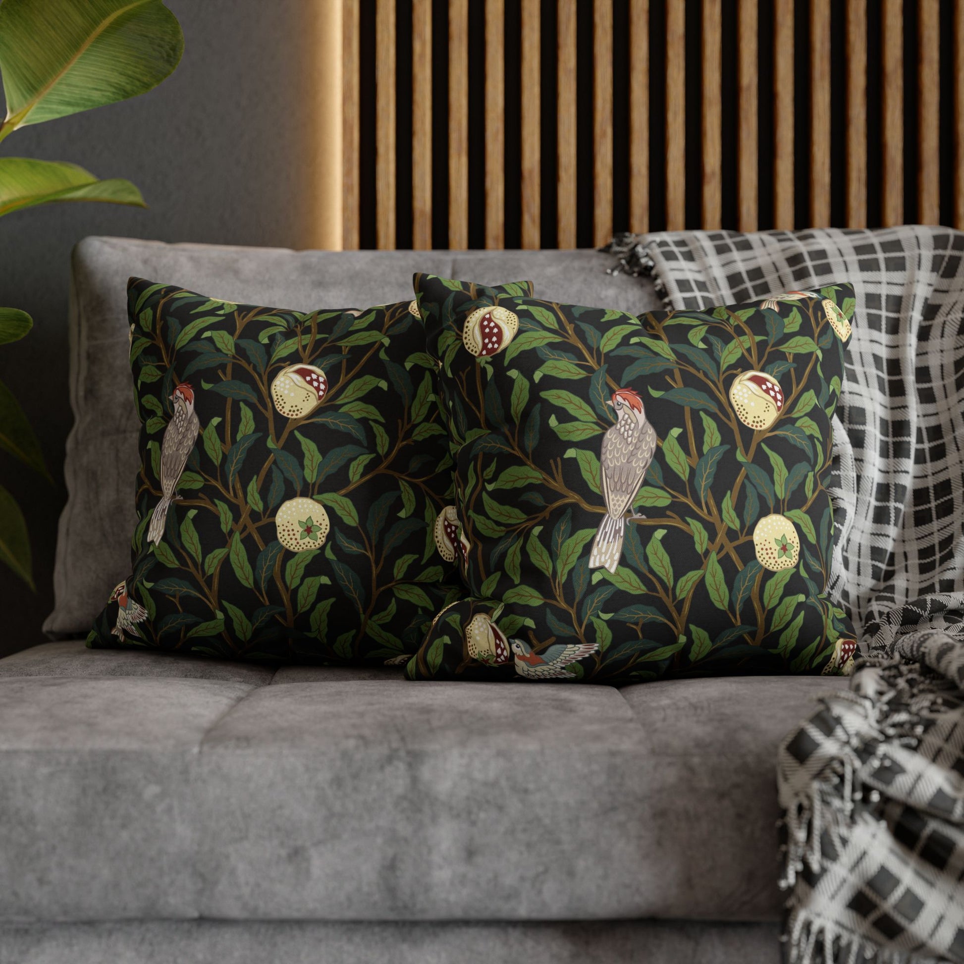Decorative pillows with bird and leaf pattern on a gray sofa.