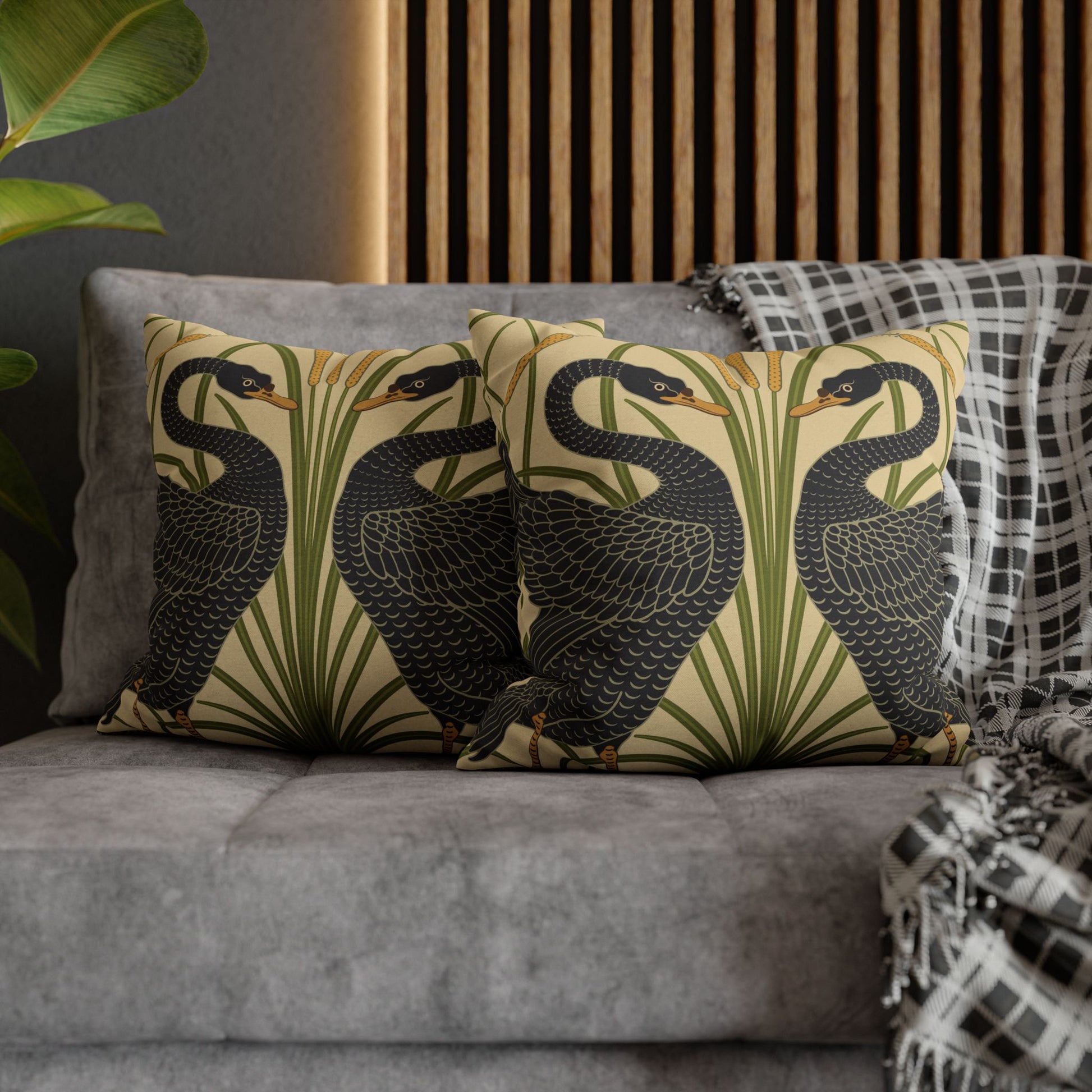 Decorative pillows with bird pattern on a gray sofa against a wooden panel wall.