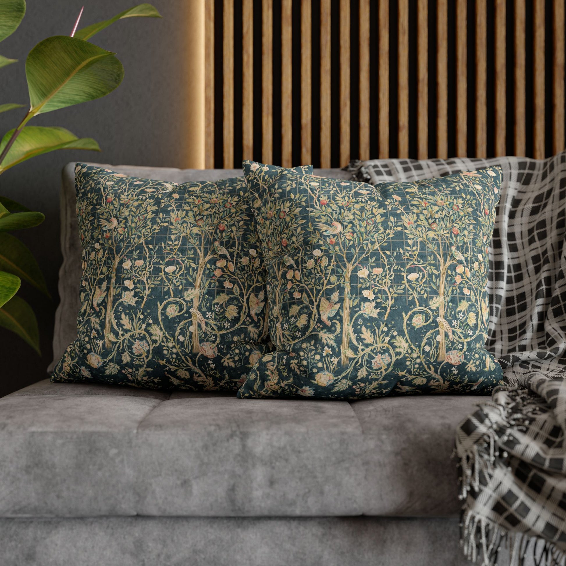 Decorative pillows with floral patterns on a gray sofa against a wooden panel wall.