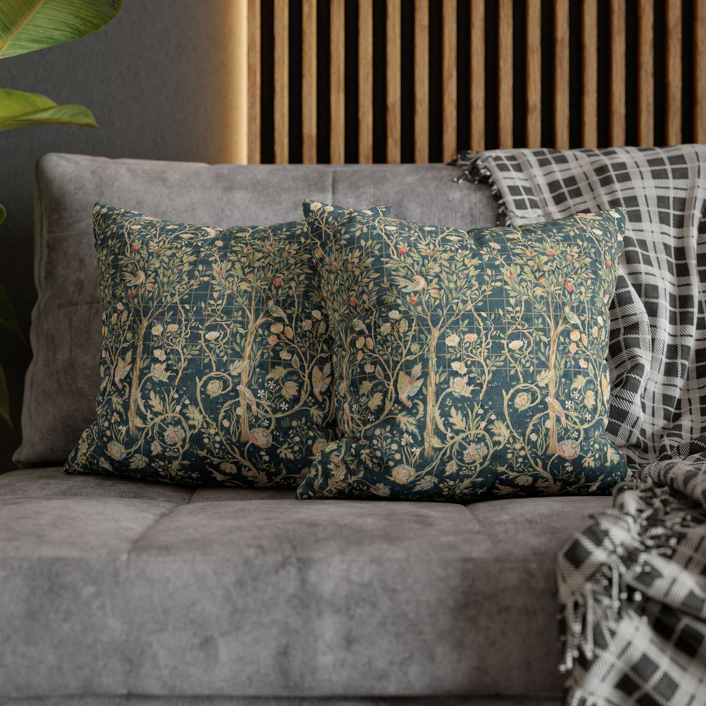 Decorative pillows with floral patterns on a gray sofa against a wooden panel wall.