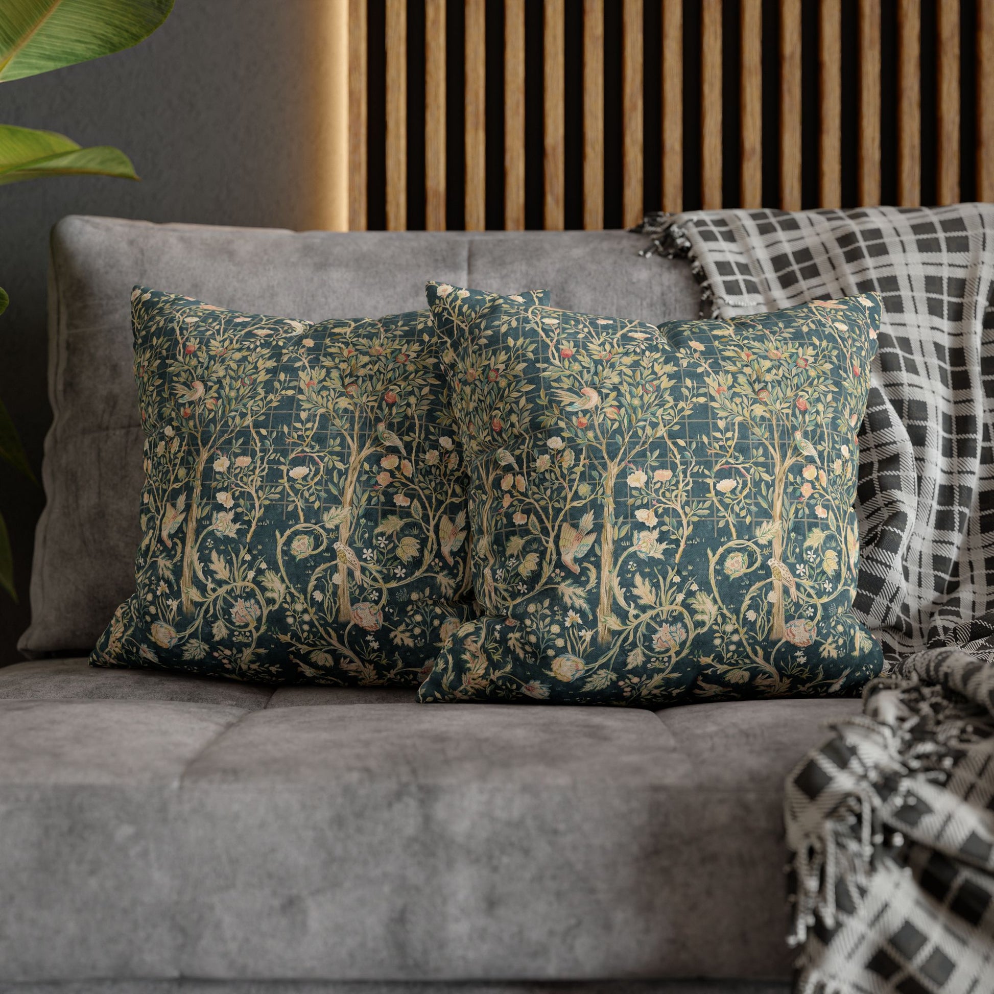 Decorative pillows with floral patterns on a gray sofa against a wooden panel wall.