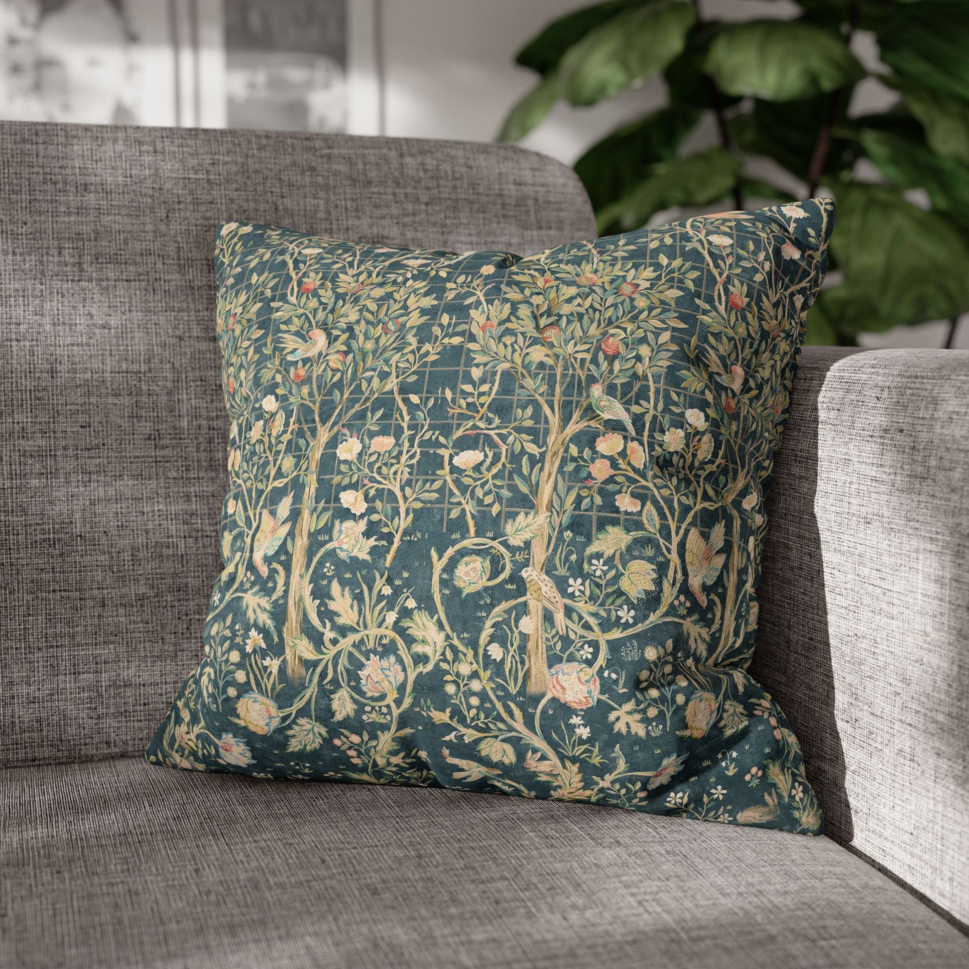 Floral patterned pillow on a gray sofa with a blurred plant in the background