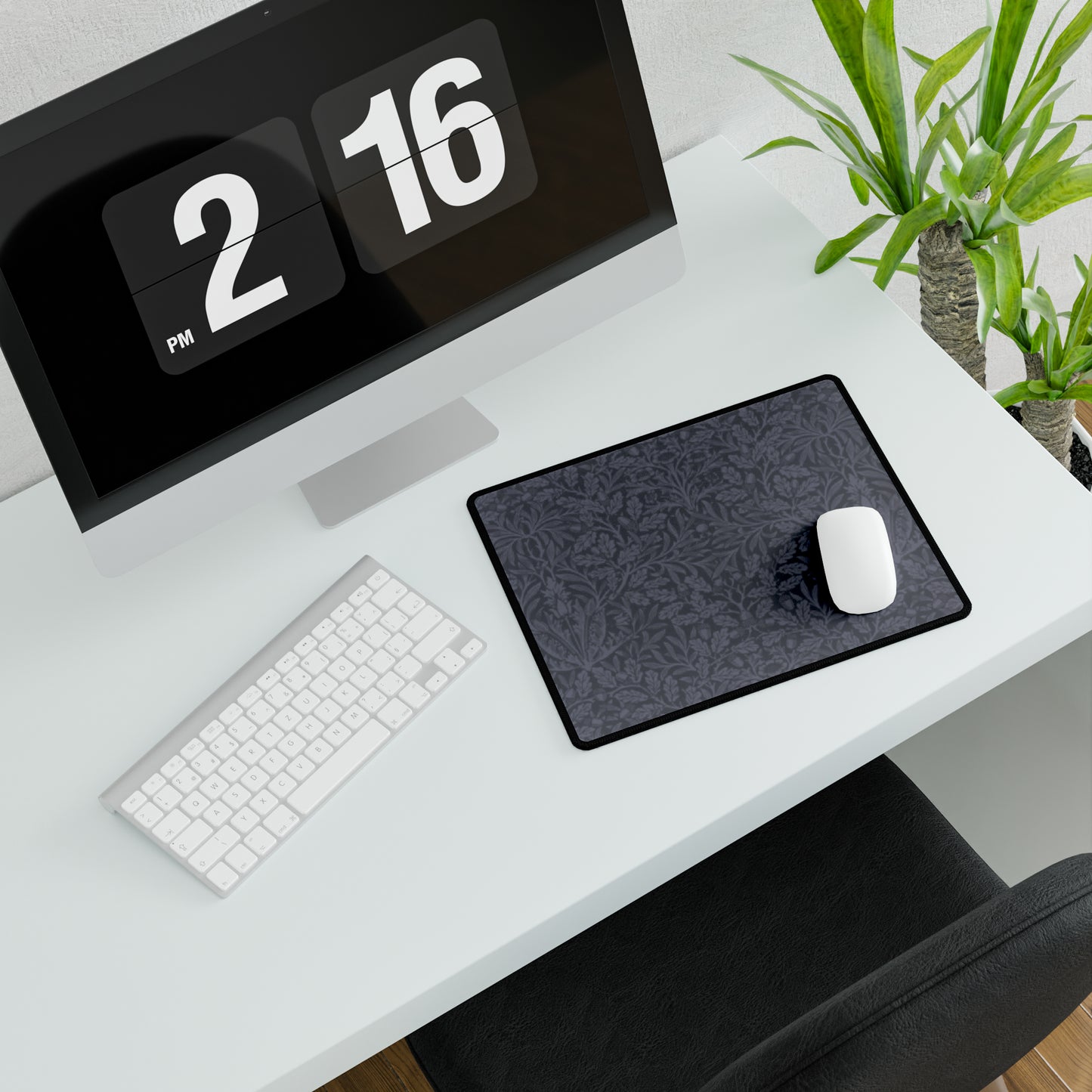 A large desk mat with an acorn and oak leaf pattern in smokey blue, displayed on a desk with a keyboard and mouse.