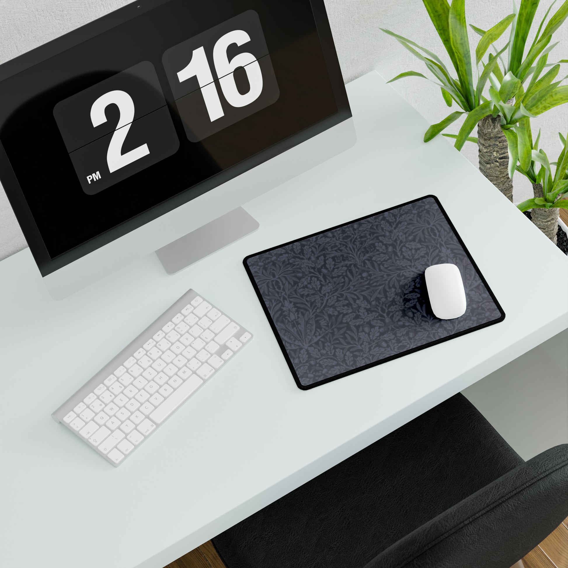A large desk mat with an acorn and oak leaf pattern in smokey blue, displayed on a desk with a keyboard and mouse.