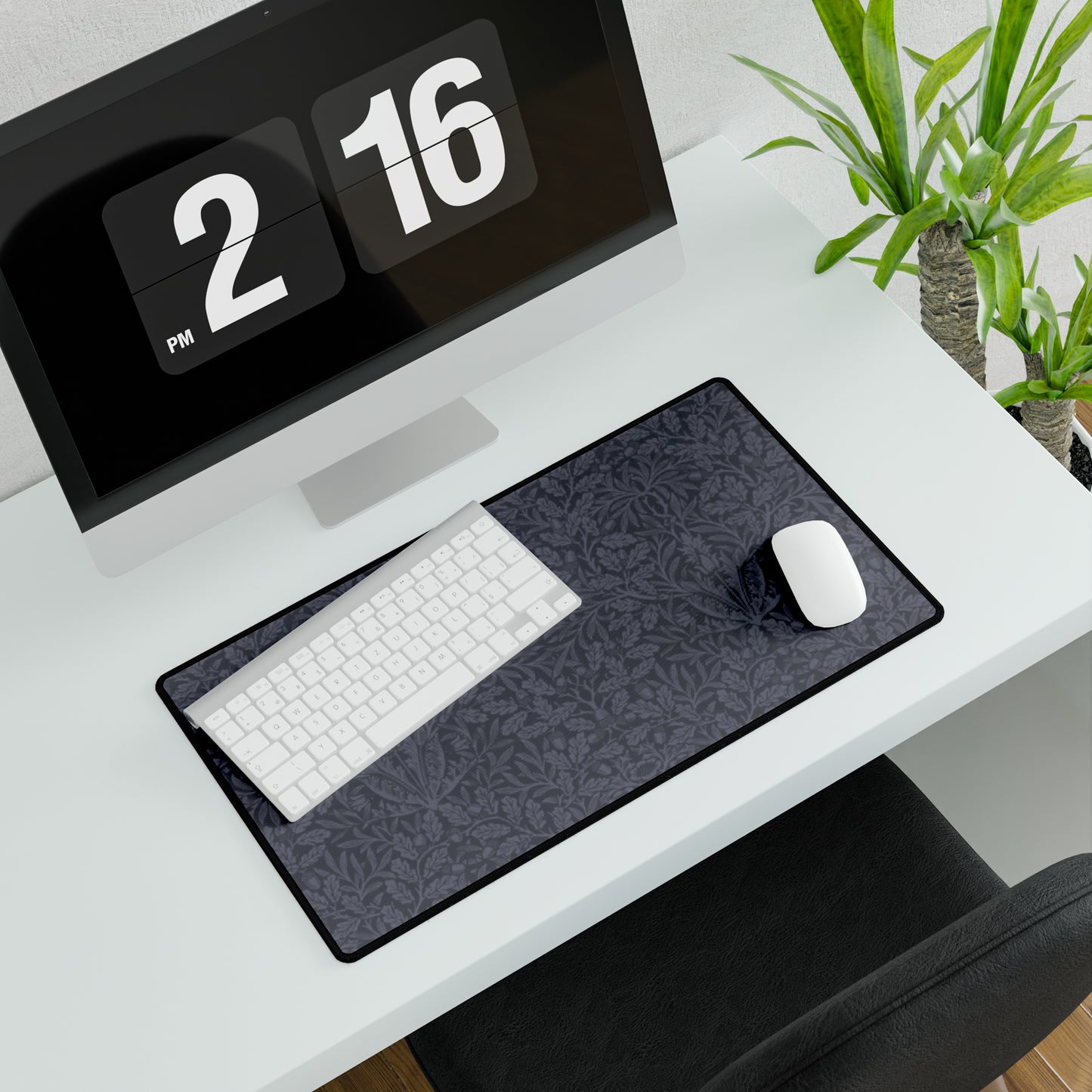 A large desk mat with an acorn and oak leaf pattern in smokey blue, displayed on a desk with a keyboard and mouse.