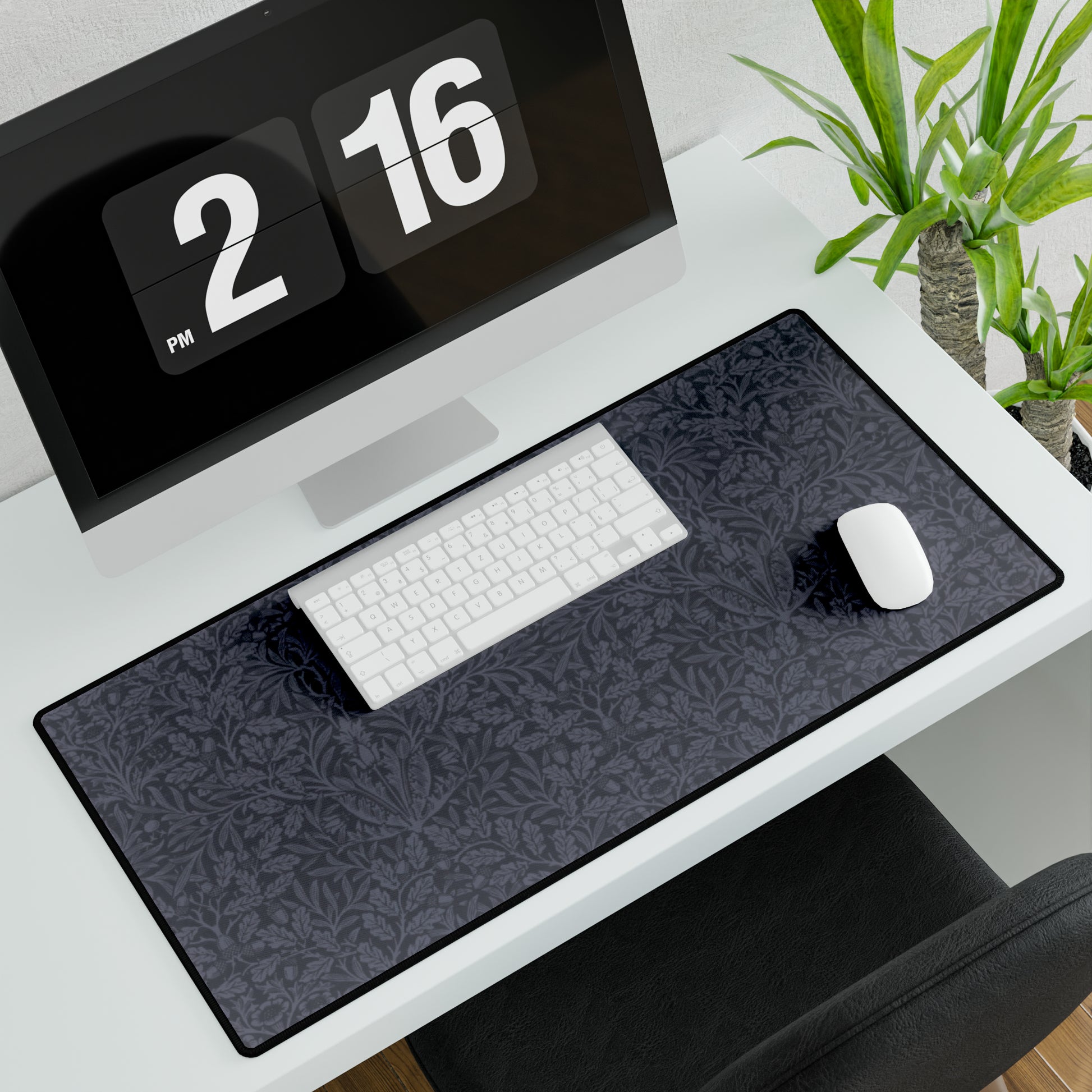 A large desk mat with an acorn and oak leaf pattern in smokey blue, displayed on a desk with a keyboard and mouse.