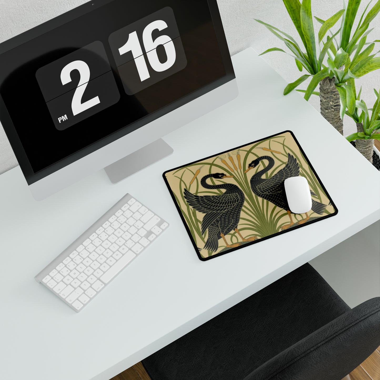 A large desk mat with a pattern of black swans, placed on a desk under a keyboard and a mouse, with a monitor mounted on the desk.