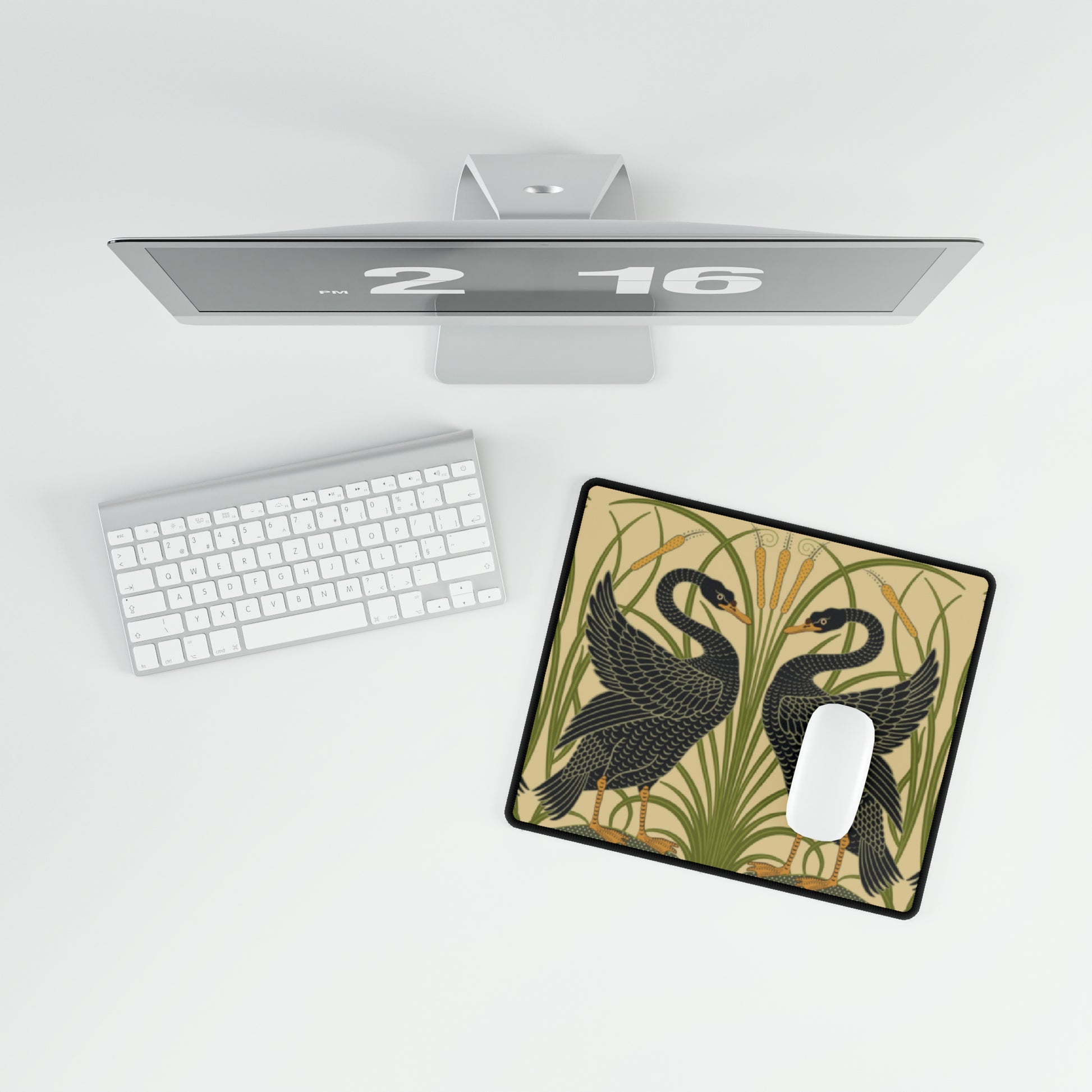 A large desk mat with a pattern of black swans, placed on a desk under a keyboard and a mouse, with a monitor mounted on the desk.
