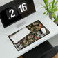A rectangular desk mat with a William Morris & Co floral pattern in multiple colours, placed under a desk with a keyboard and mouse on top.